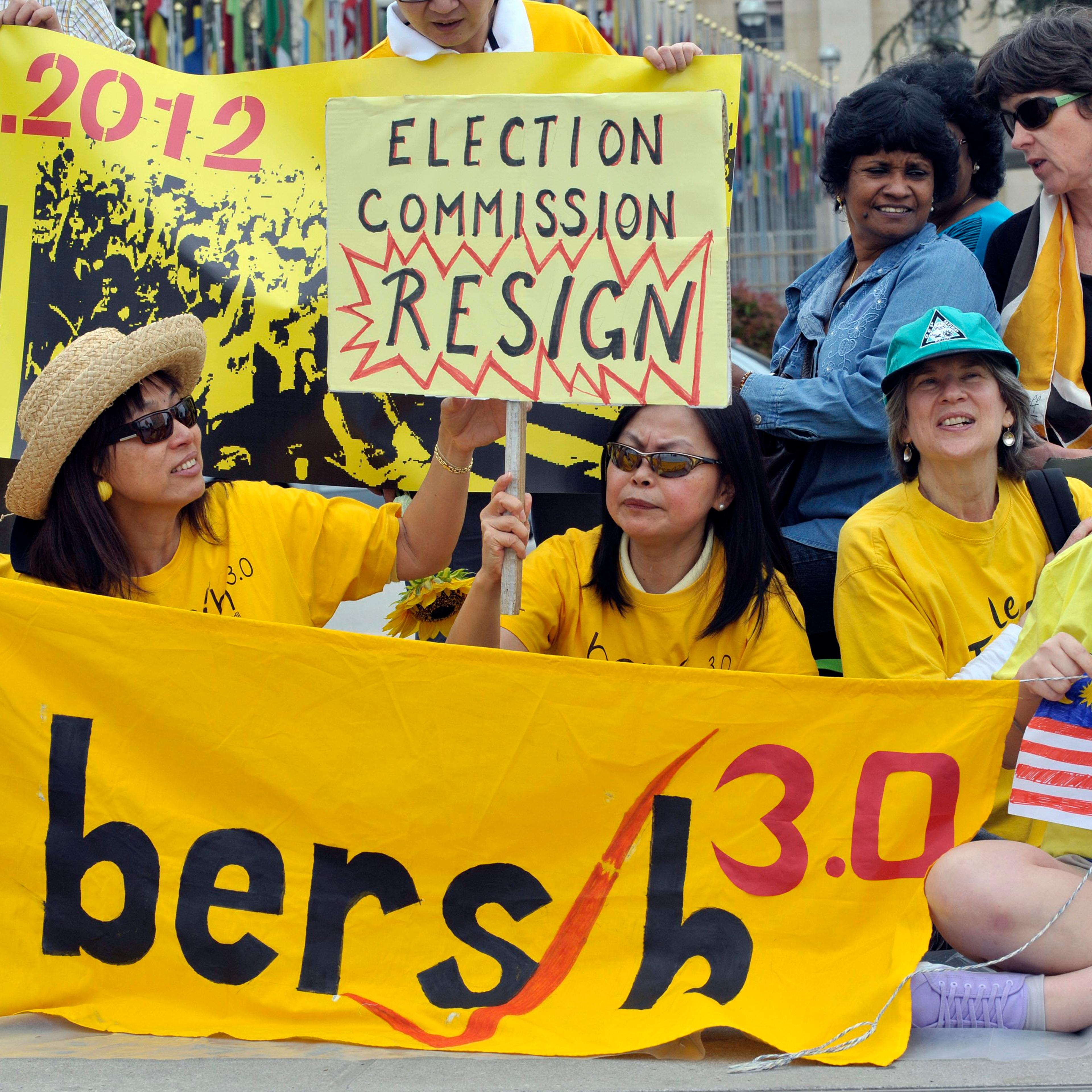 Demonstrators of the Malayan movement Bersih for democracy hold banners to ask for free and fair elections in Malaysia in front of the European headquarters of the United Nations in Geneva on April 28, 2012.