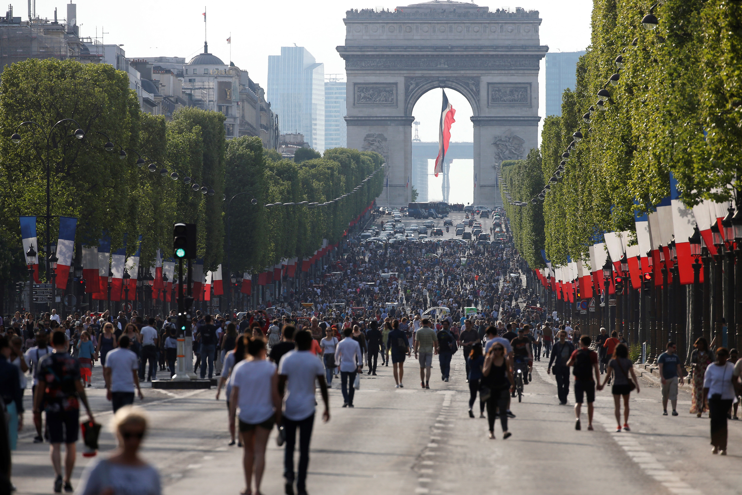 People walk along the Champs Elysees Avenue on May 8, 2016, as the French capital's most famous avenue goes car-free for a day, in the first instalment of a monthly effort to tackle pollution in Paris. / AFP / THOMAS SAMSON (Photo credit should read THOM