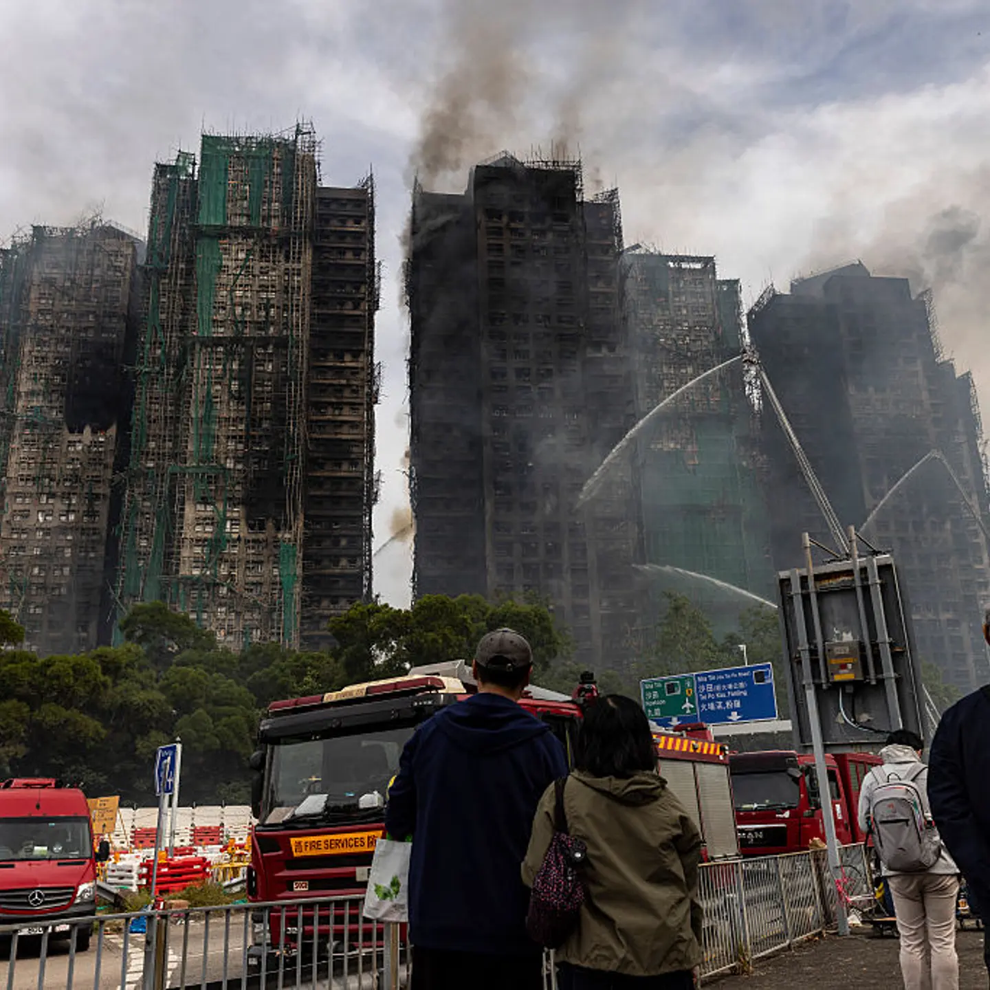People watch as residential buildings continue to burn at Wang Fuk Court in the Tai Po district in Hong Kong, China, on Nov. 27, 2025