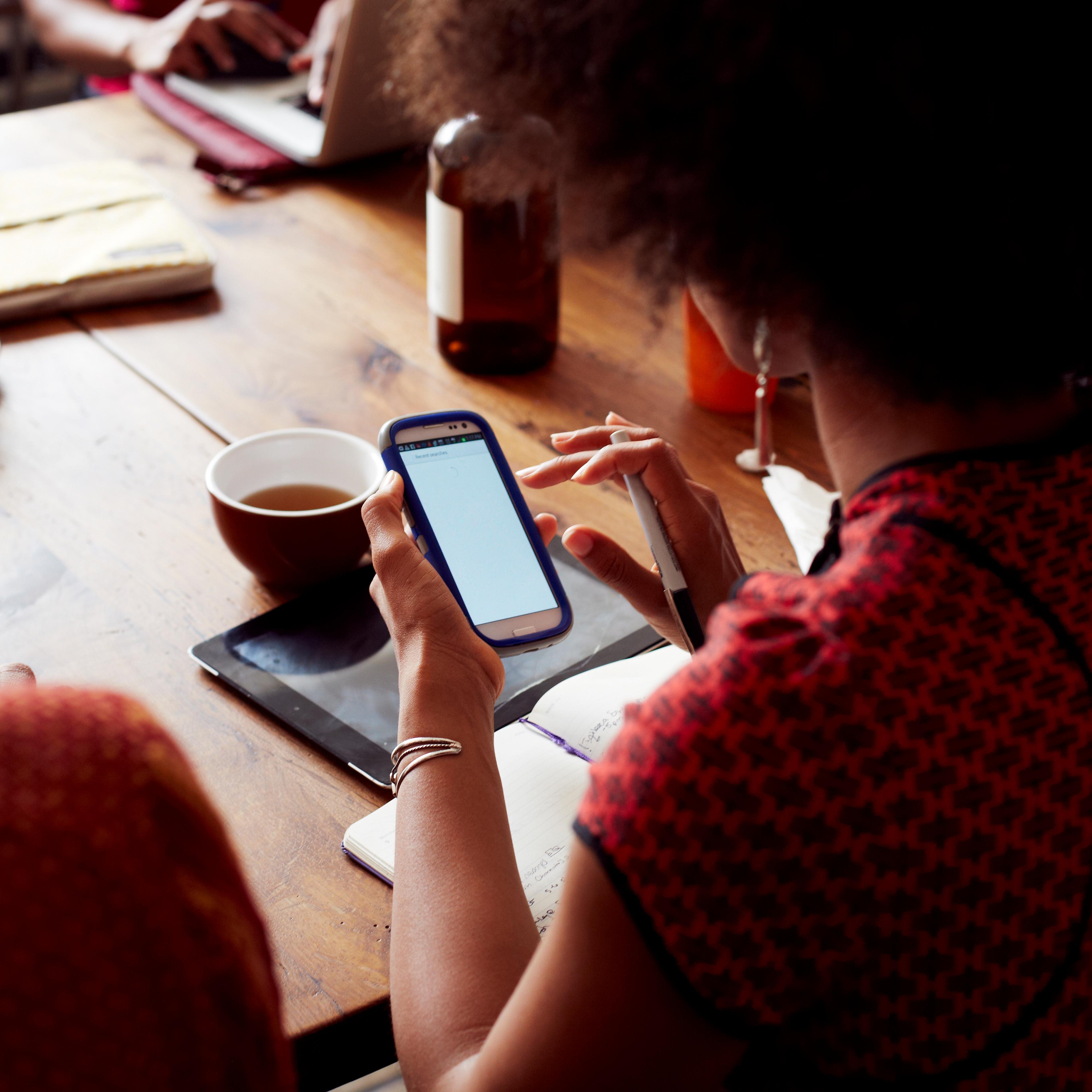 Businesswoman using cell phone in cafe