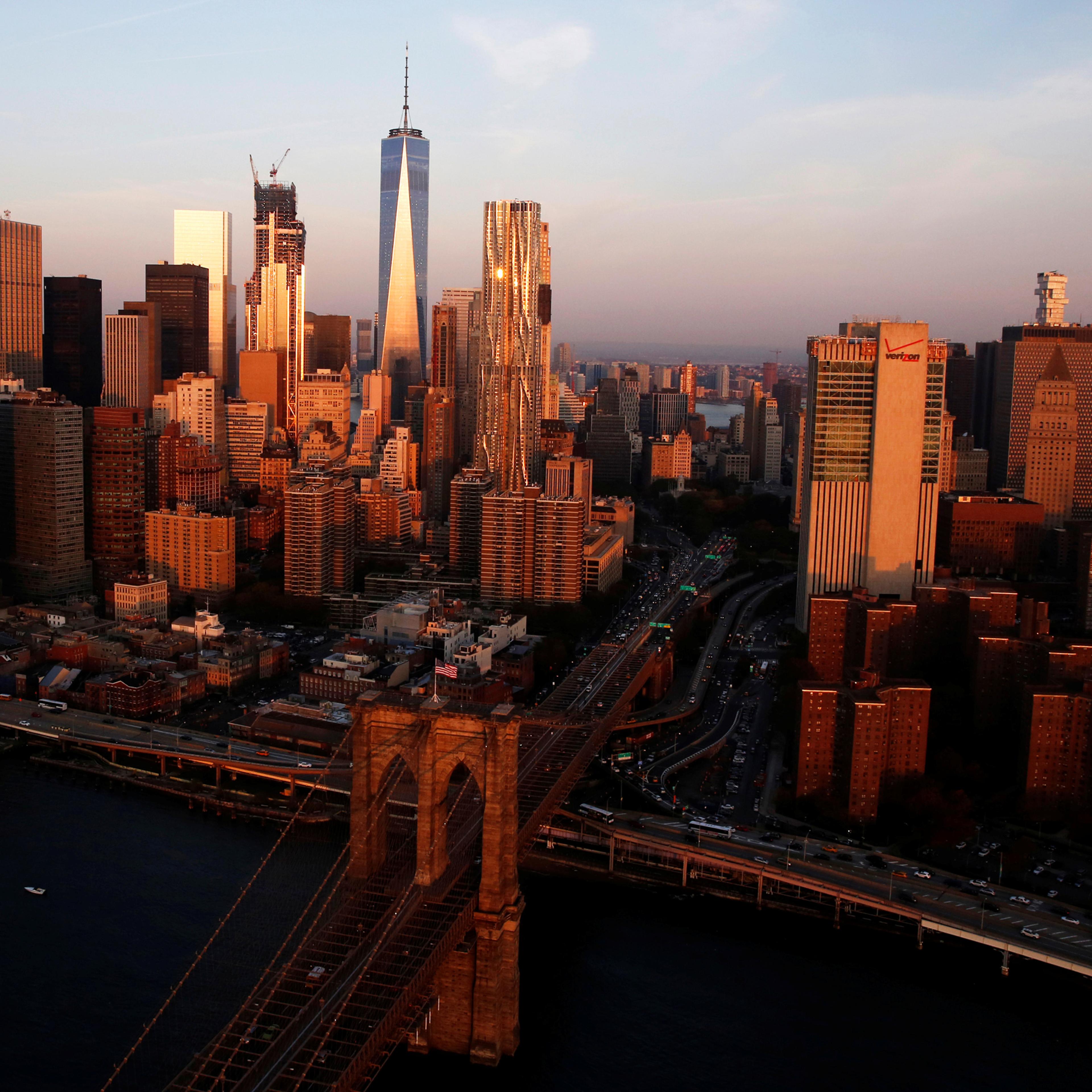 The rising sun lights the Brooklyn Bridge and One World Trade in the Manhattan borough of New York