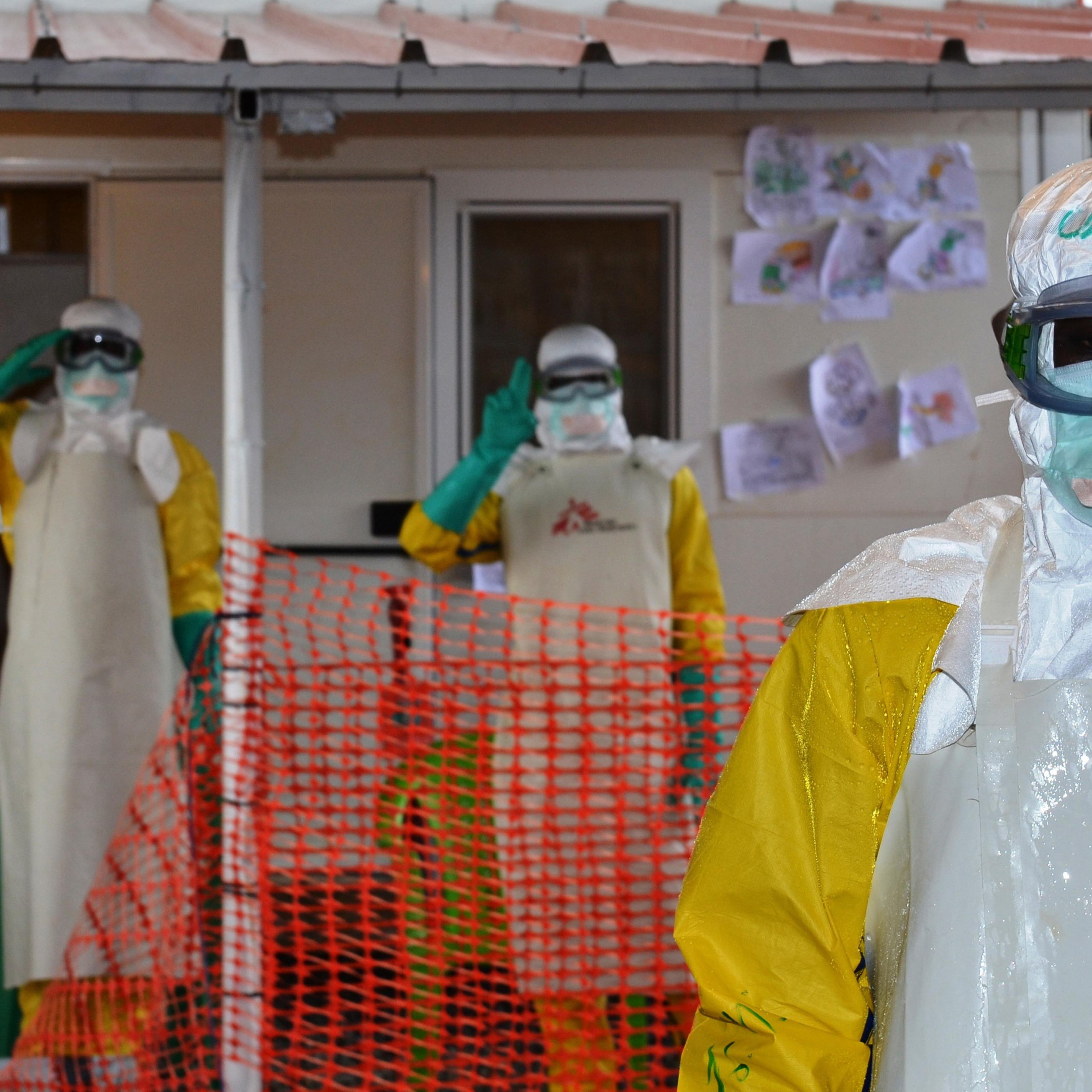 Health workers wearing protective gear gesture at the Nongo ebola treatment centre in Conakry, Guinea, on August 21, 2015.