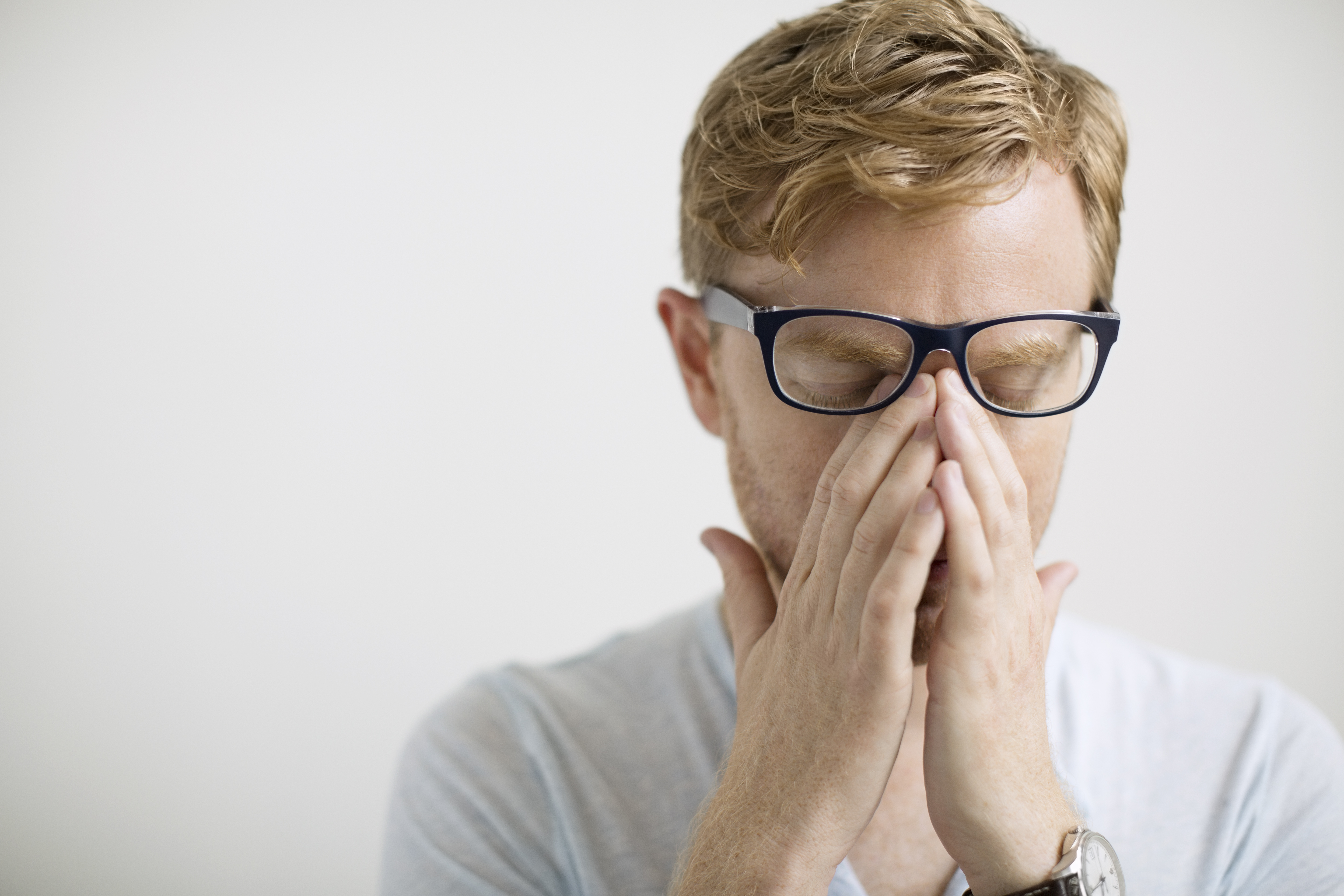 man rubbing eyes under eyeglasses