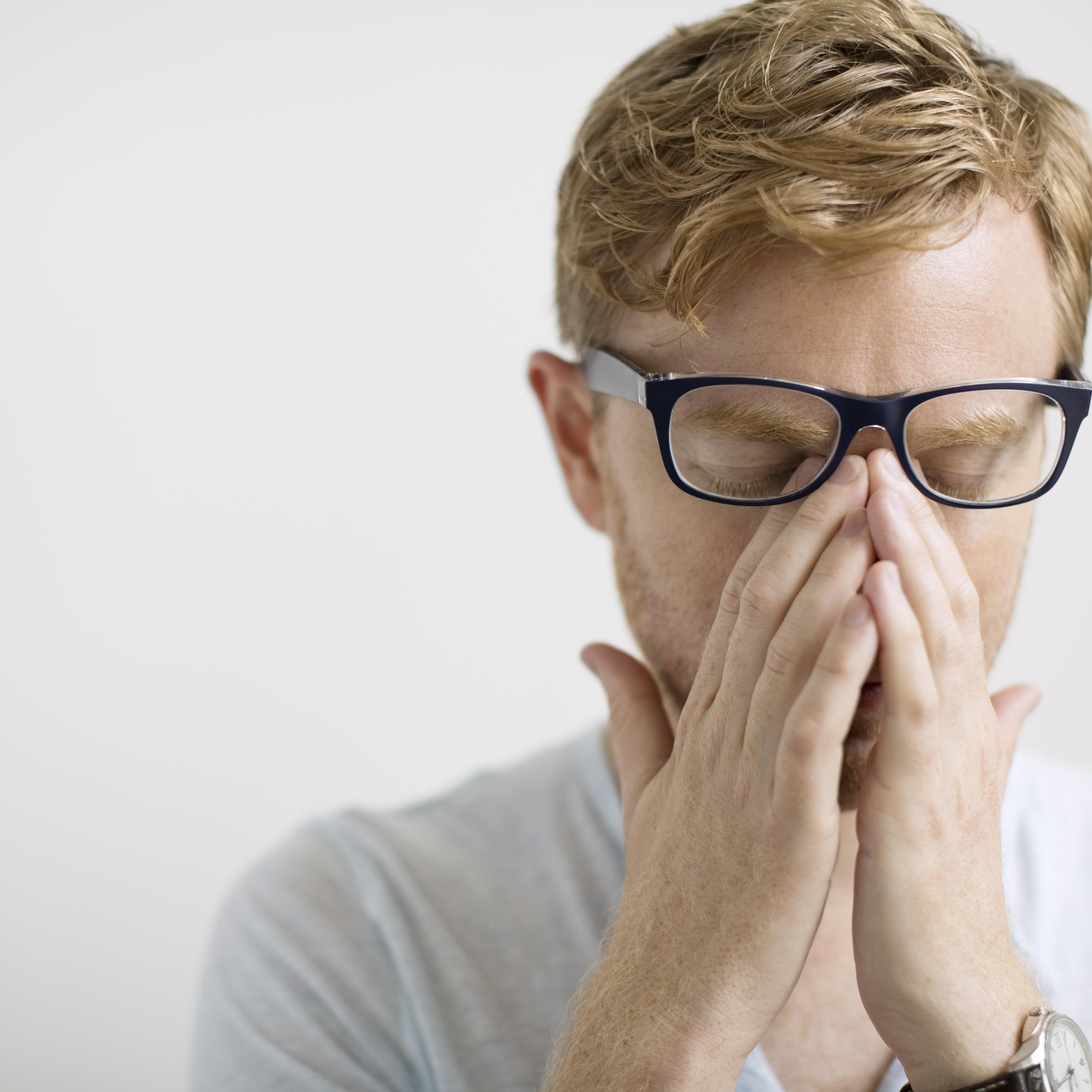 man rubbing eyes under eyeglasses