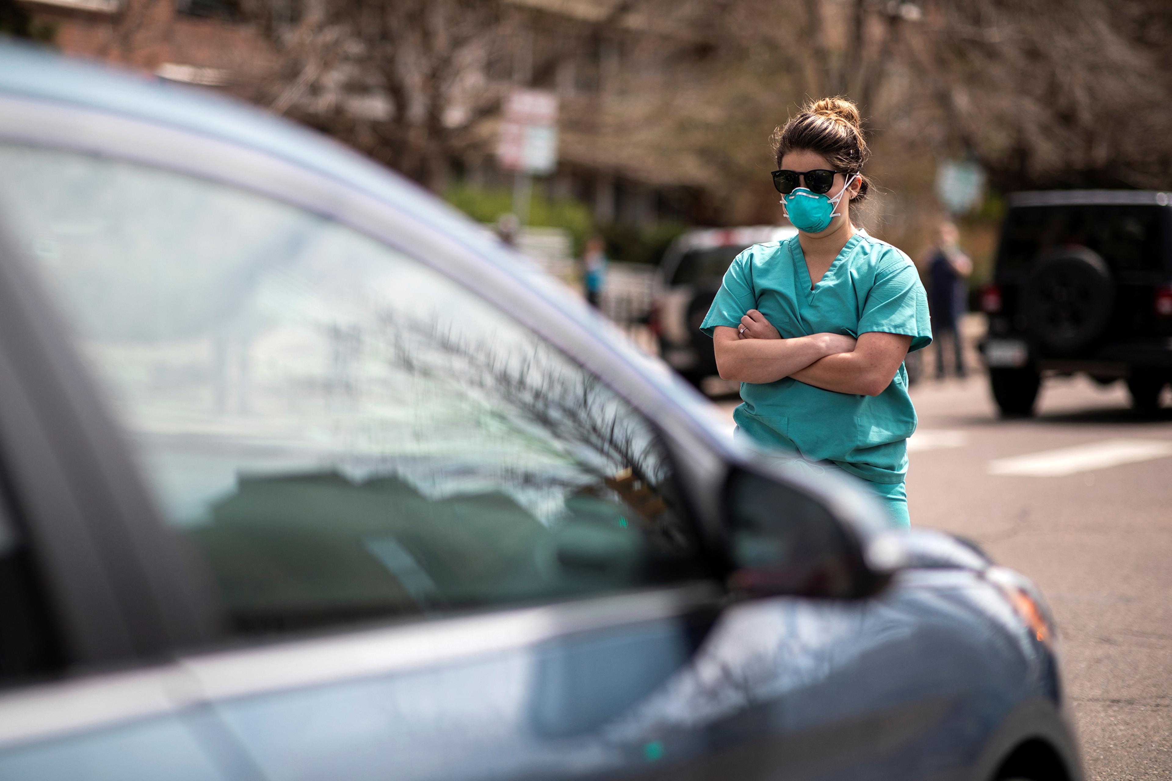 Health care workers stand in the street as a counter-protest to those demanding the stay-at-home order be lifted in Denver