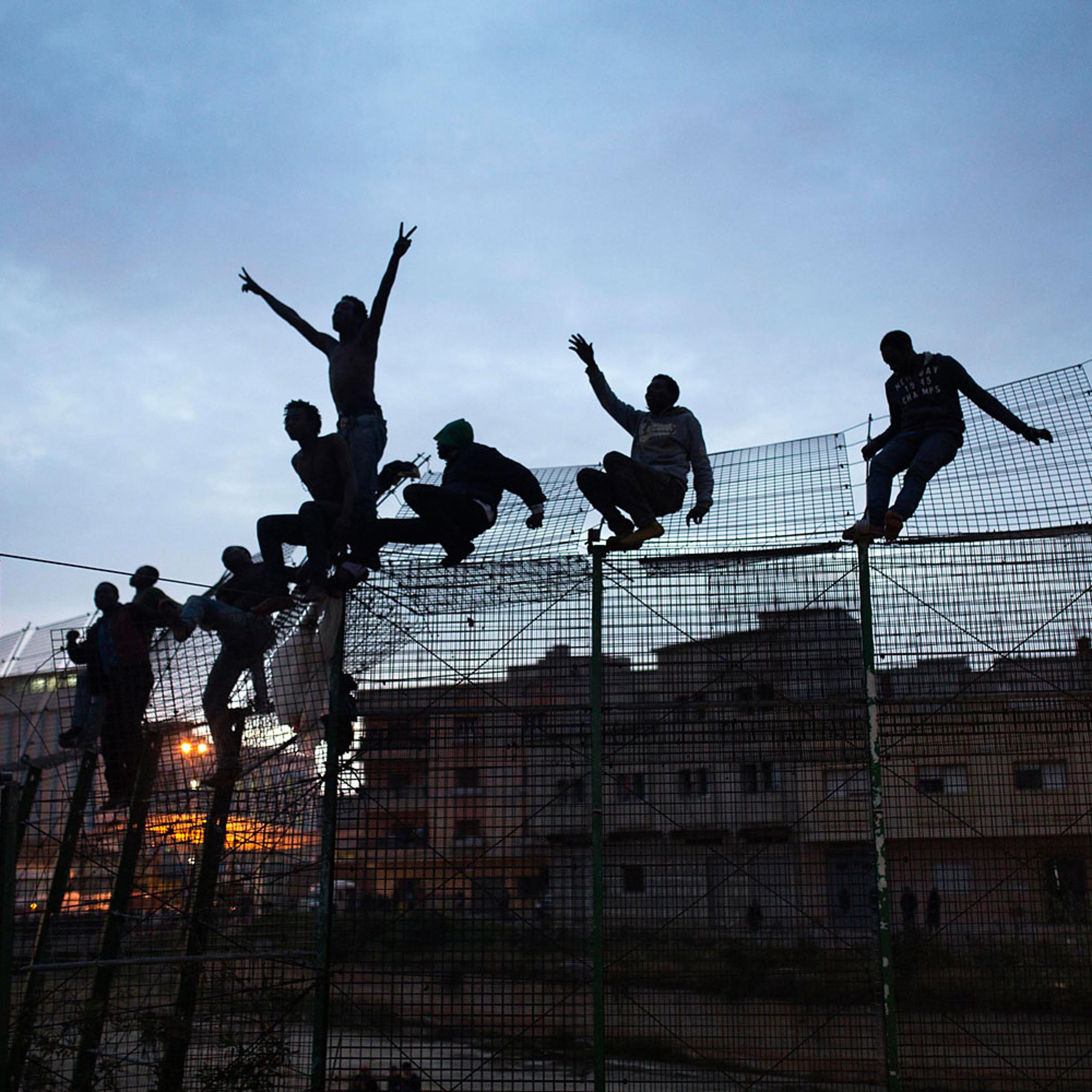 Sub-Saharan migrants climb over a metallic fence that divides Morocco and the Spanish enclave of Melilla, March 28, 2014.