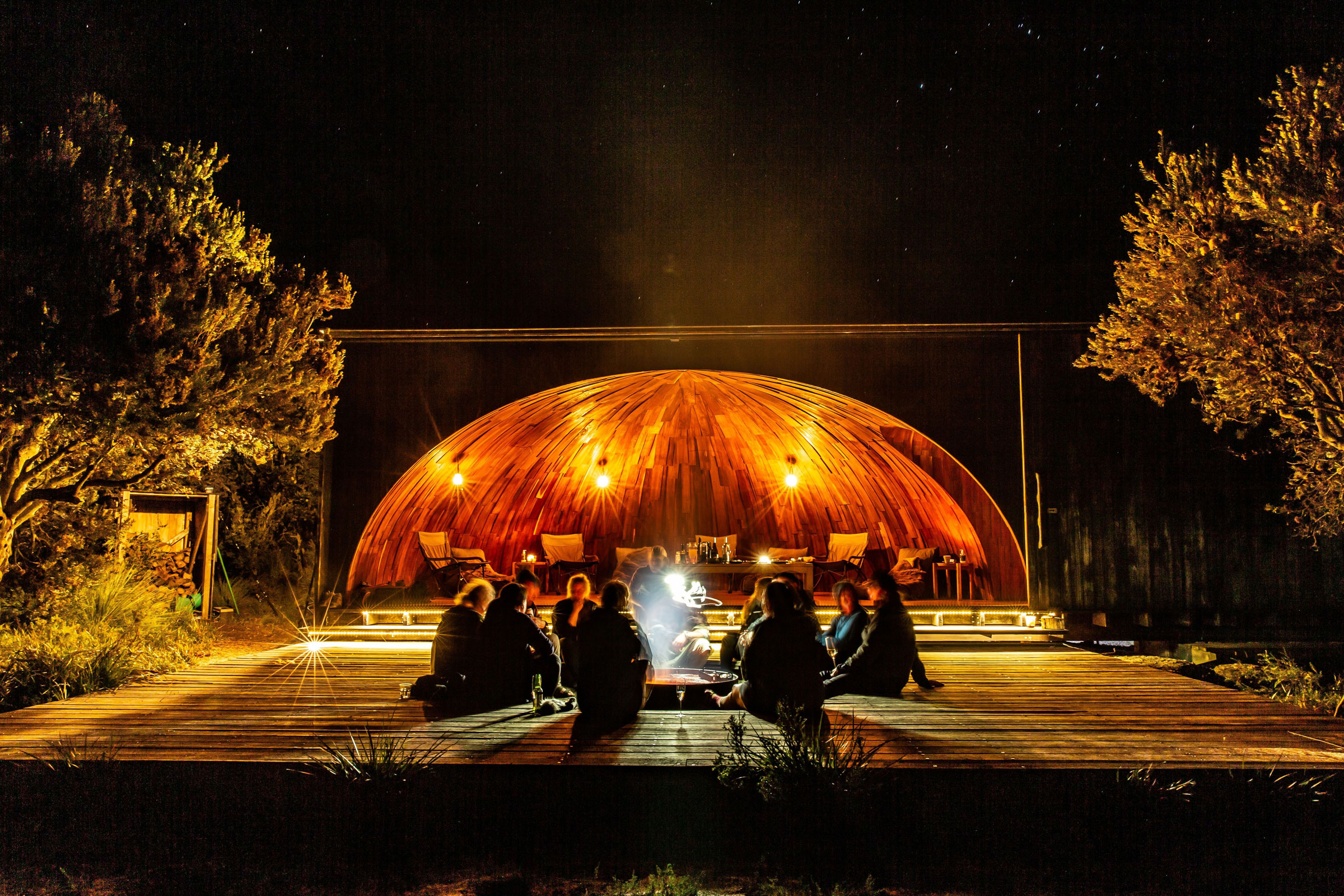Guides and guests gather around the open fire at krakani lumi (place of rest) standing camp.