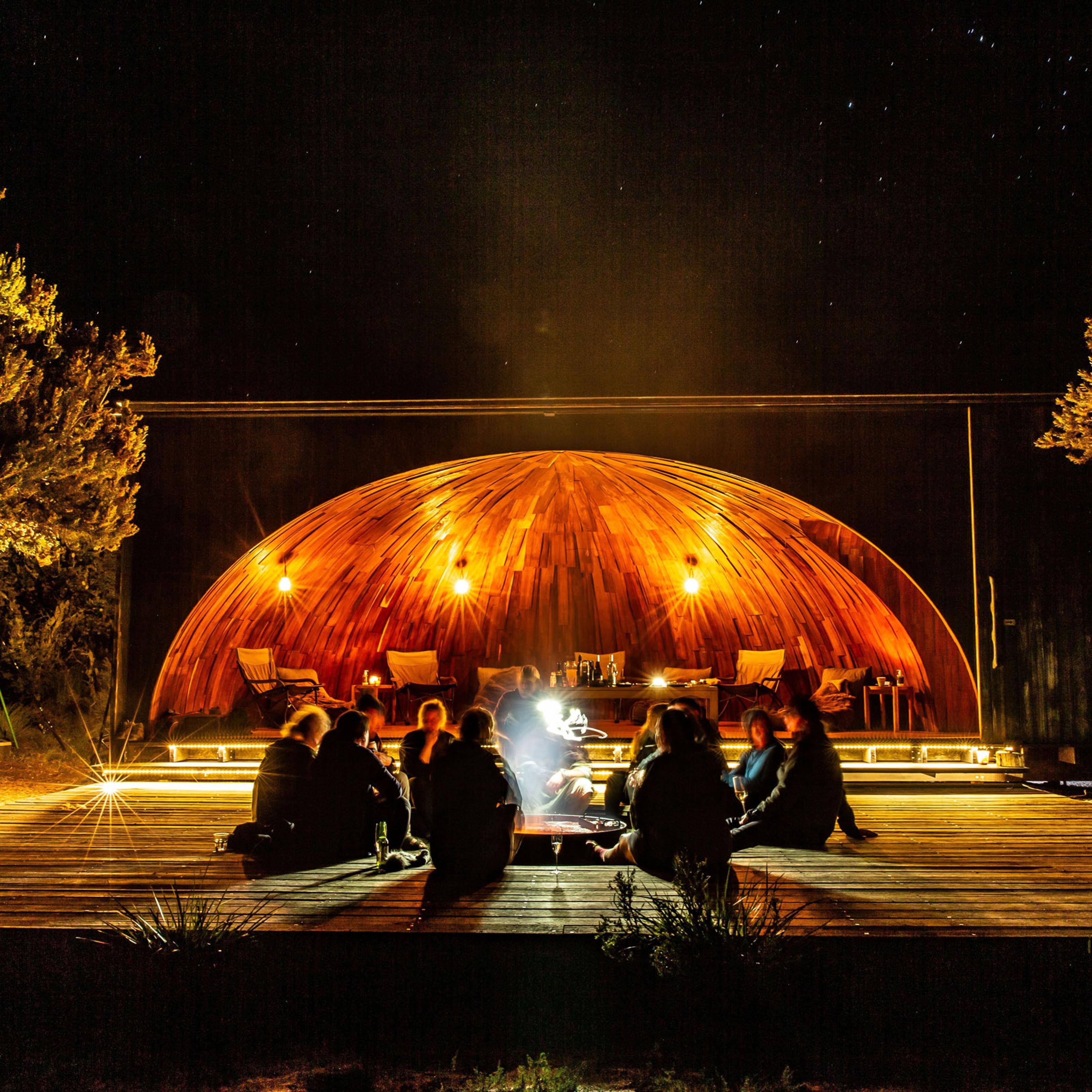 Guides and guests gather around the open fire at krakani lumi (place of rest) standing camp.