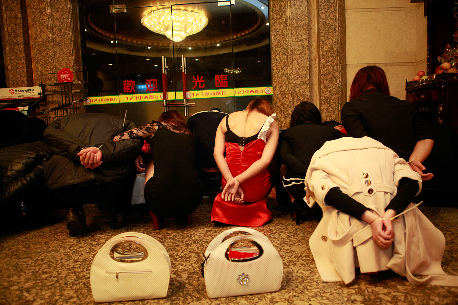 This picture taken late on Feb. 9, 2014 shows alleged sex workers and clients detained by Chinese police after a raid on an entertainment center in Dongguan, southern China's Guangdong province