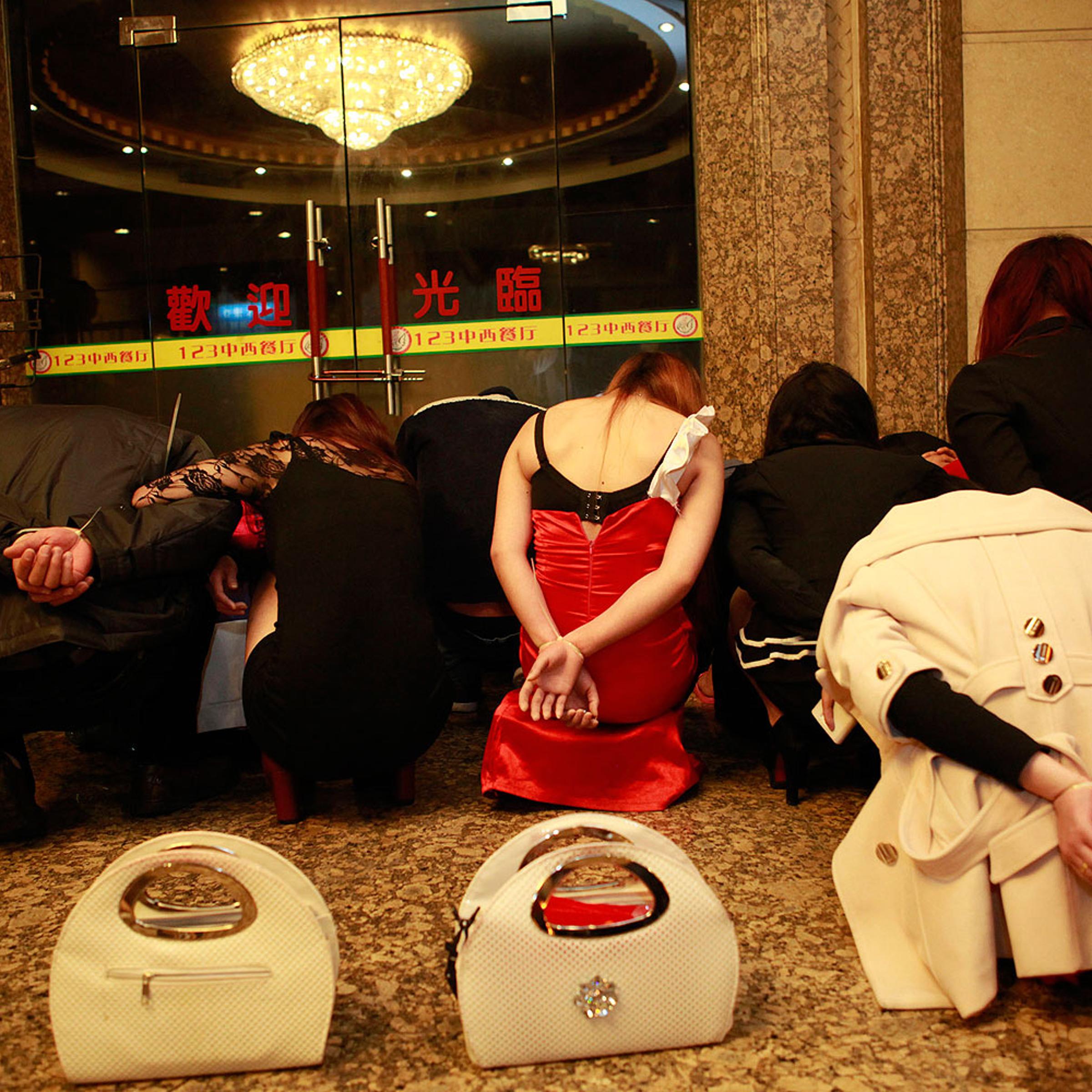 This picture taken late on Feb. 9, 2014 shows alleged sex workers and clients detained by Chinese police after a raid on an entertainment center in Dongguan, southern China's Guangdong province
