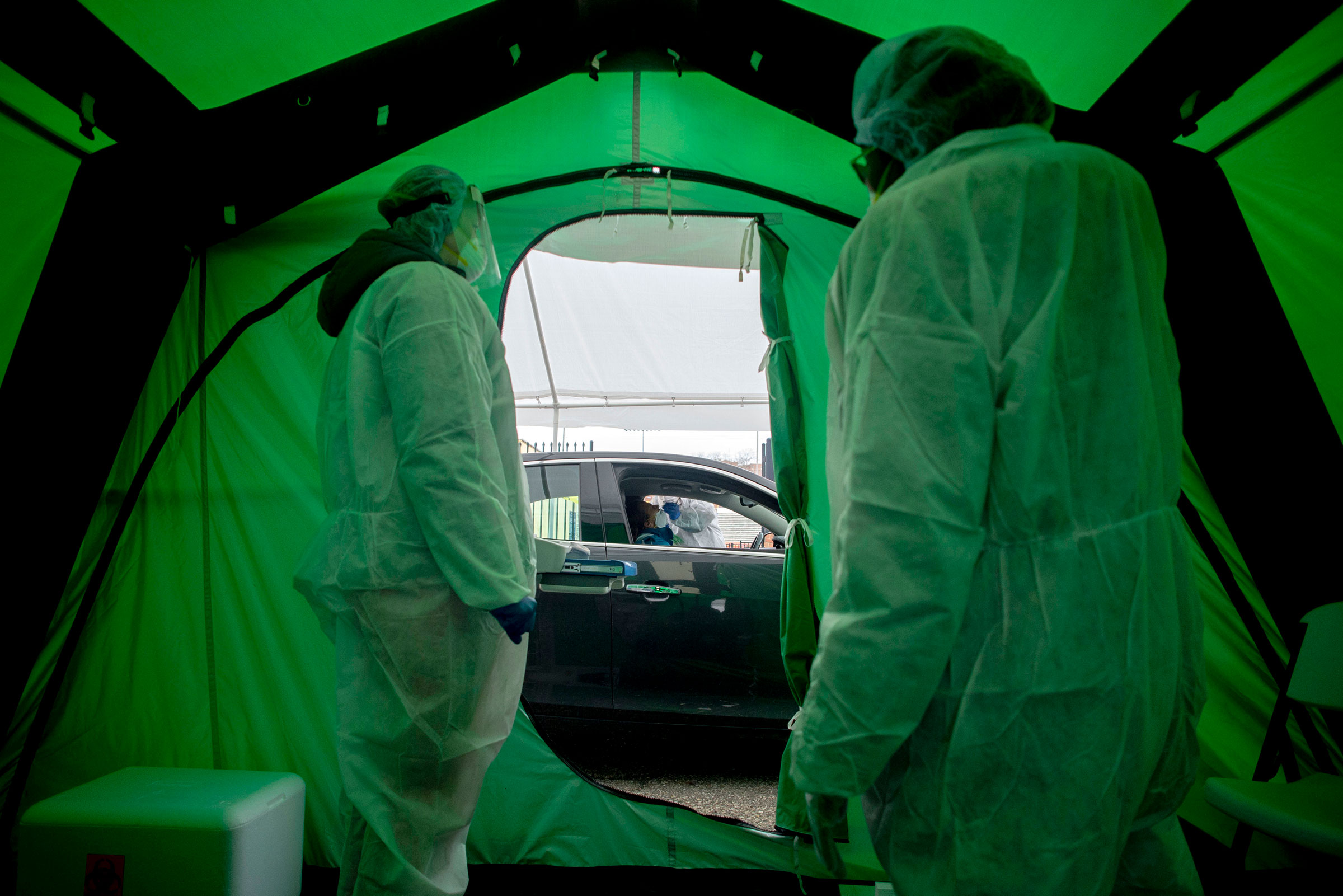 Medical workers watch as one of the first 50 people are tested for coronavirus at Flint
