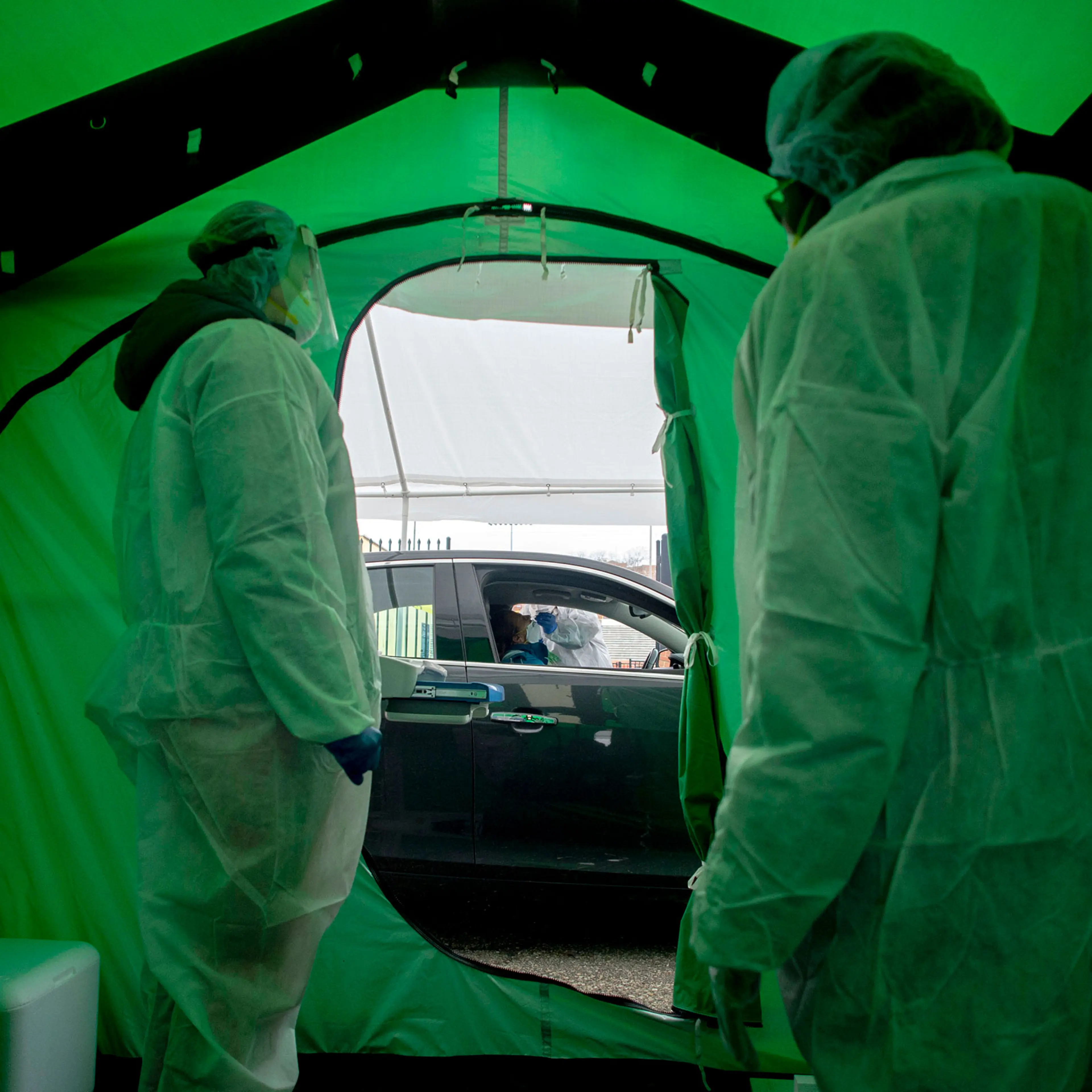 Medical workers watch as one of the first 50 people are tested for coronavirus at Flint