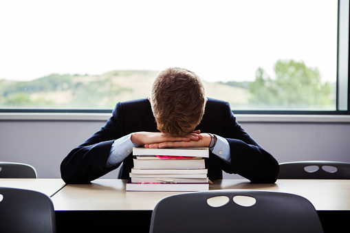 male-student-sitting-books-head-down