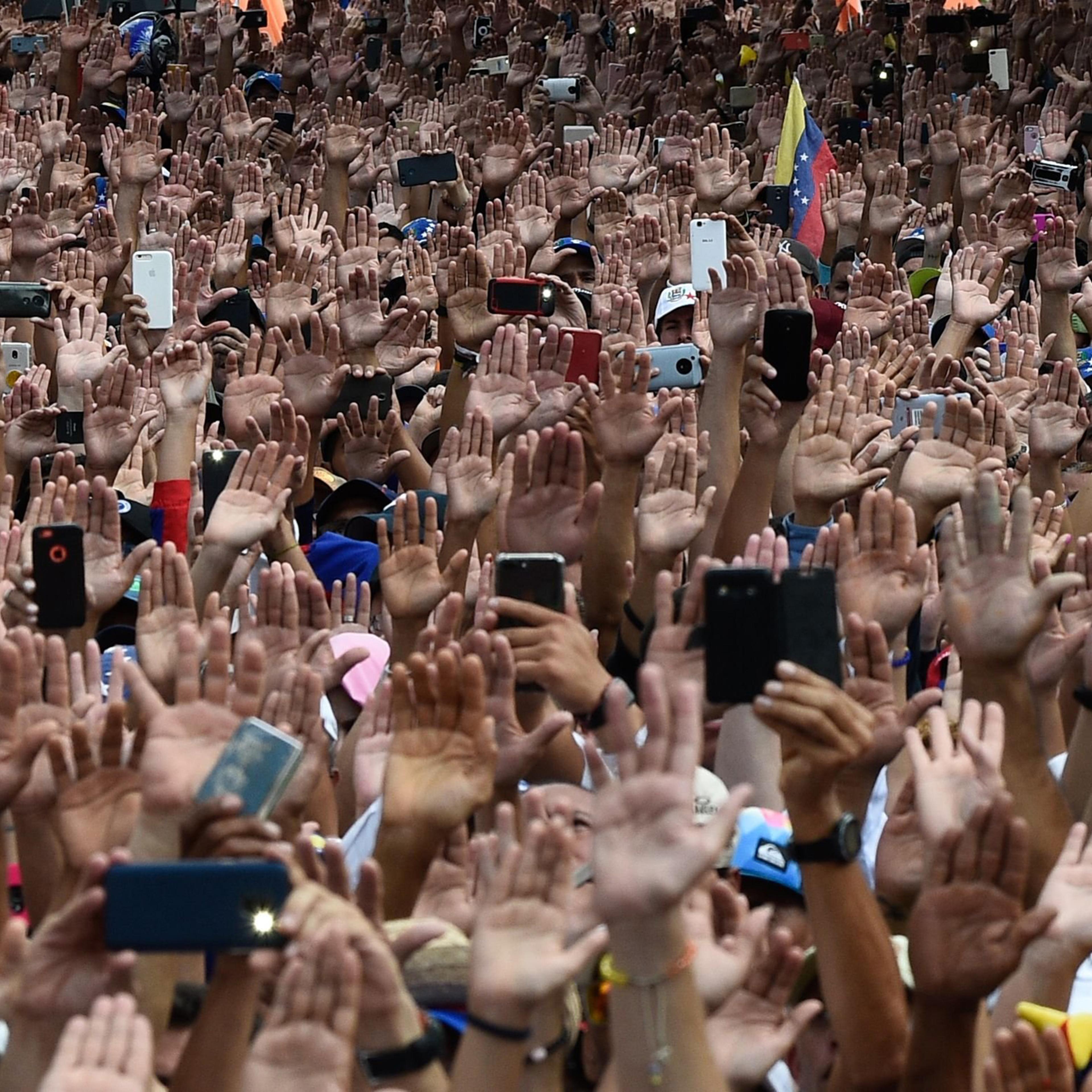People raise their hands during a massive anti-government rally against Venezuelan President Nicolás Maduro.