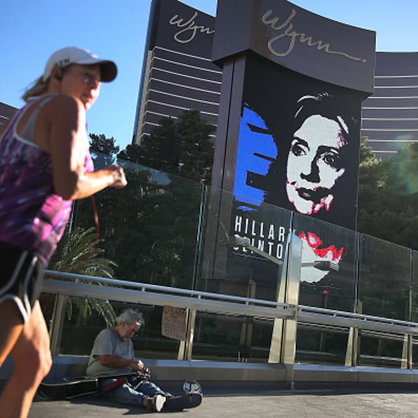 Michael McLean sets up to play his guitar for money near a billboard showing a picture of Democratic Presidential candidate Hillary Clinton advertising the upcoming Democratic Presidential debate at the Wynn Las Vegas resort and casino on October 12, 201