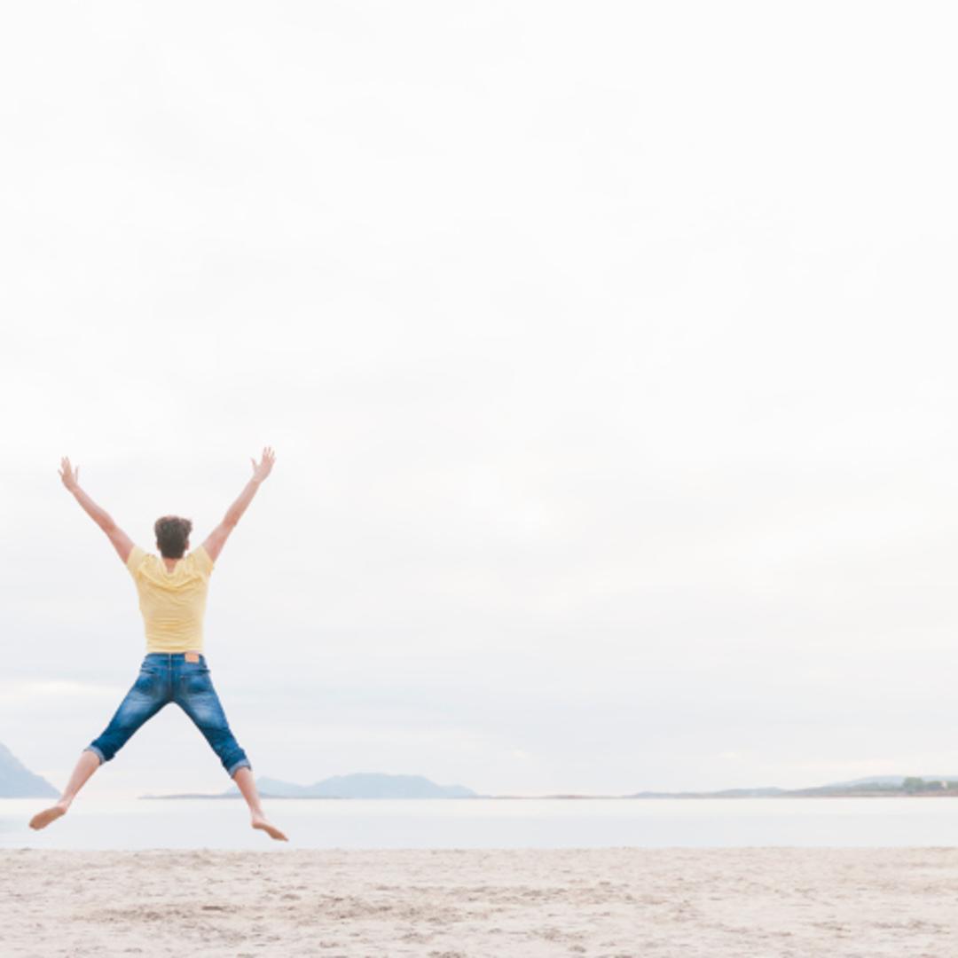 Man jumping in mid air on beach
