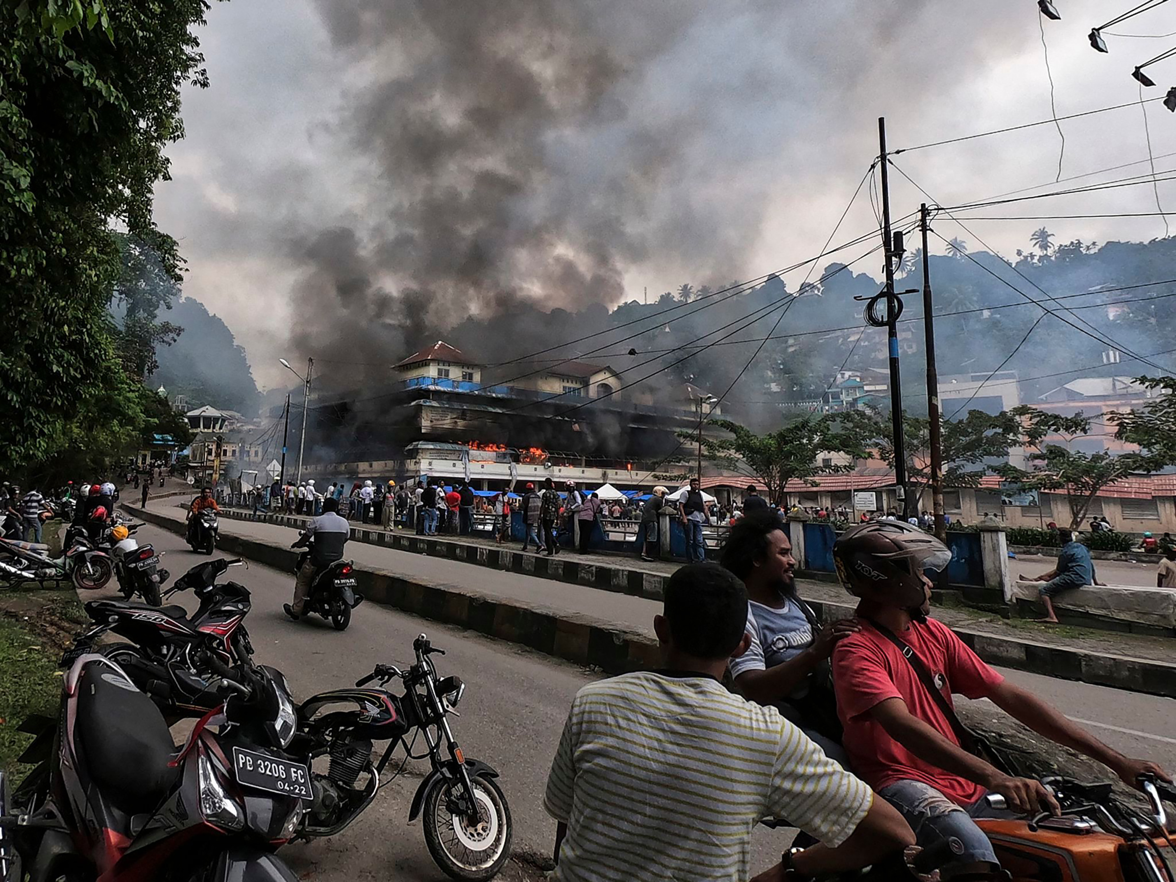 Papuans gather outside the burning Buruni market after it was torched by protesters in Fakfak, West Papua, on Aug. 21, 2019. According to media reports, the Indonesian government sent more than 1000 security personnel to West Papua as unrest, triggered b