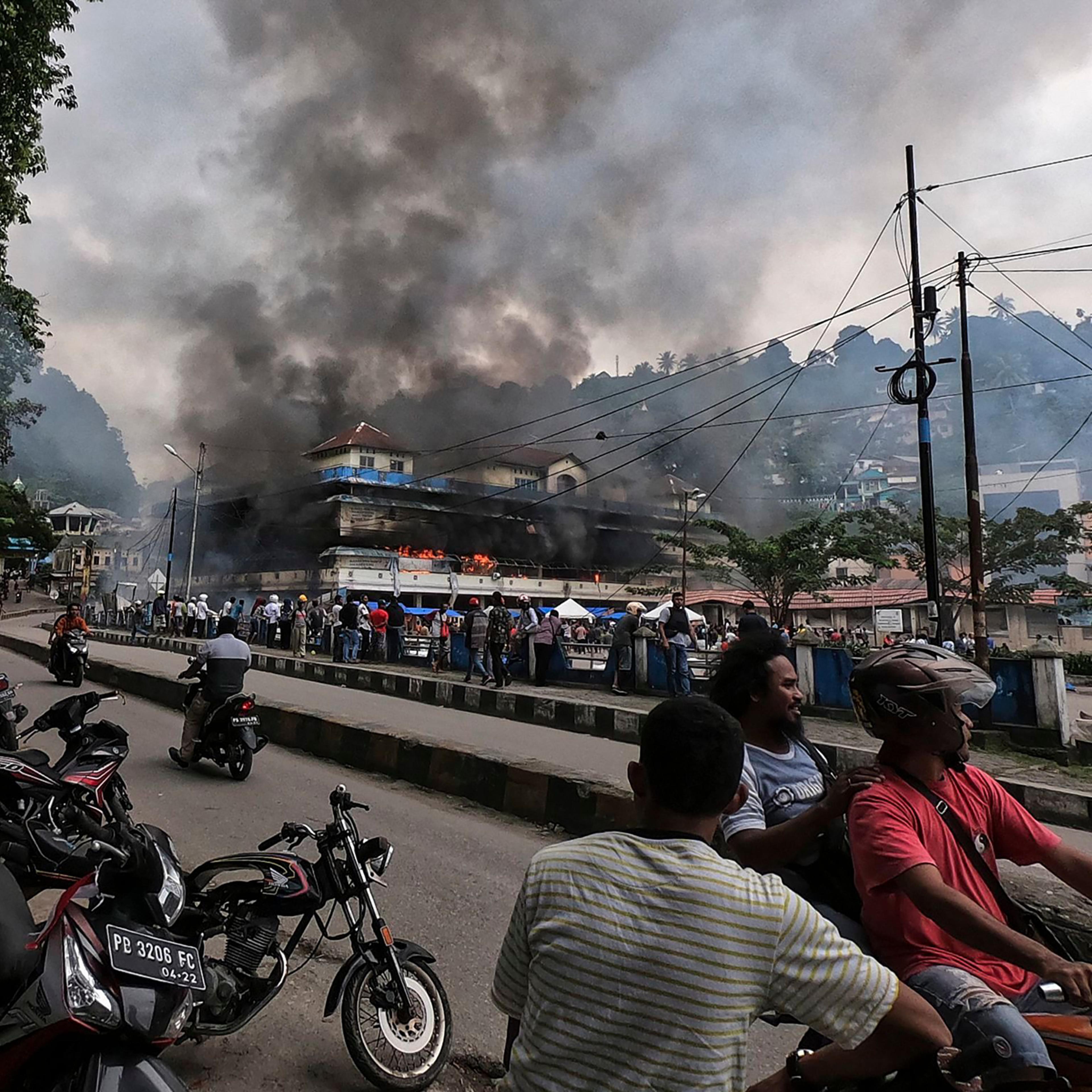 Papuans gather outside the burning Buruni market after it was torched by protesters in Fakfak, West Papua, on Aug. 21, 2019. According to media reports, the Indonesian government sent more than 1000 security personnel to West Papua as unrest, triggered b