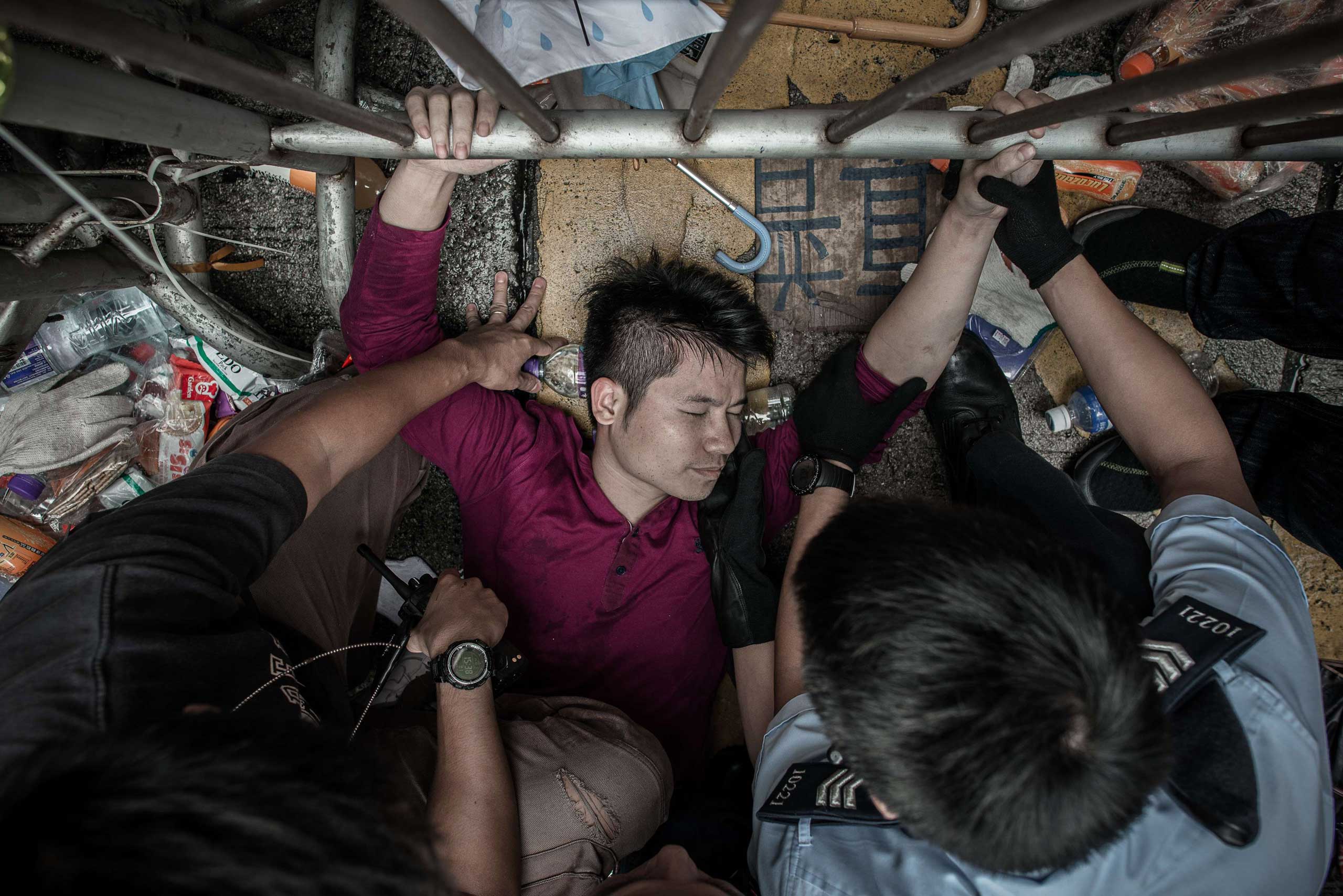 Policemen try to get a man to let go of a fence guarded by pro-democracy demonstrators in an occupied area of Hong Kong on Oct. 3, 2014.