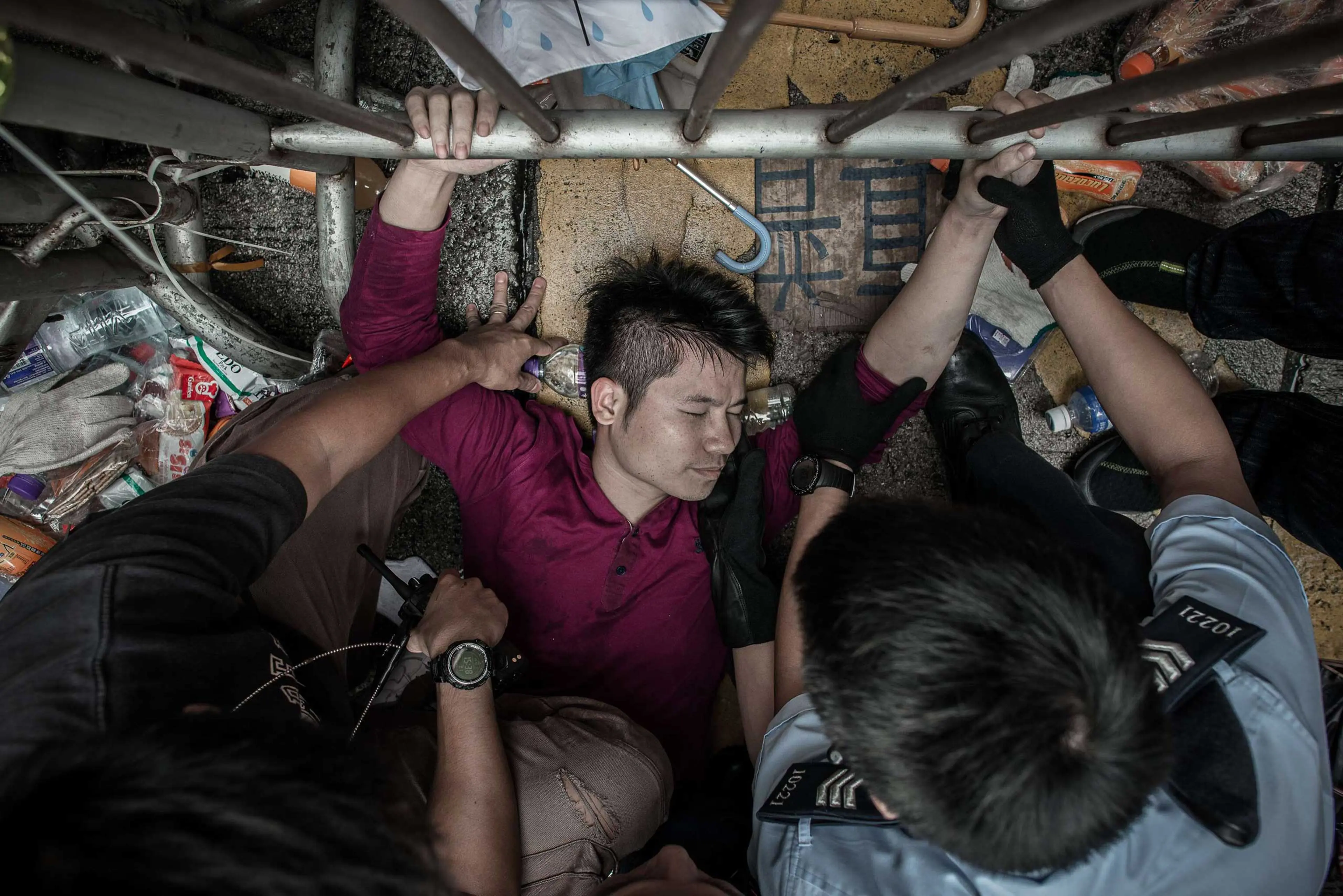Policemen try to get a man to let go of a fence guarded by pro-democracy demonstrators in an occupied area of Hong Kong on Oct. 3, 2014.