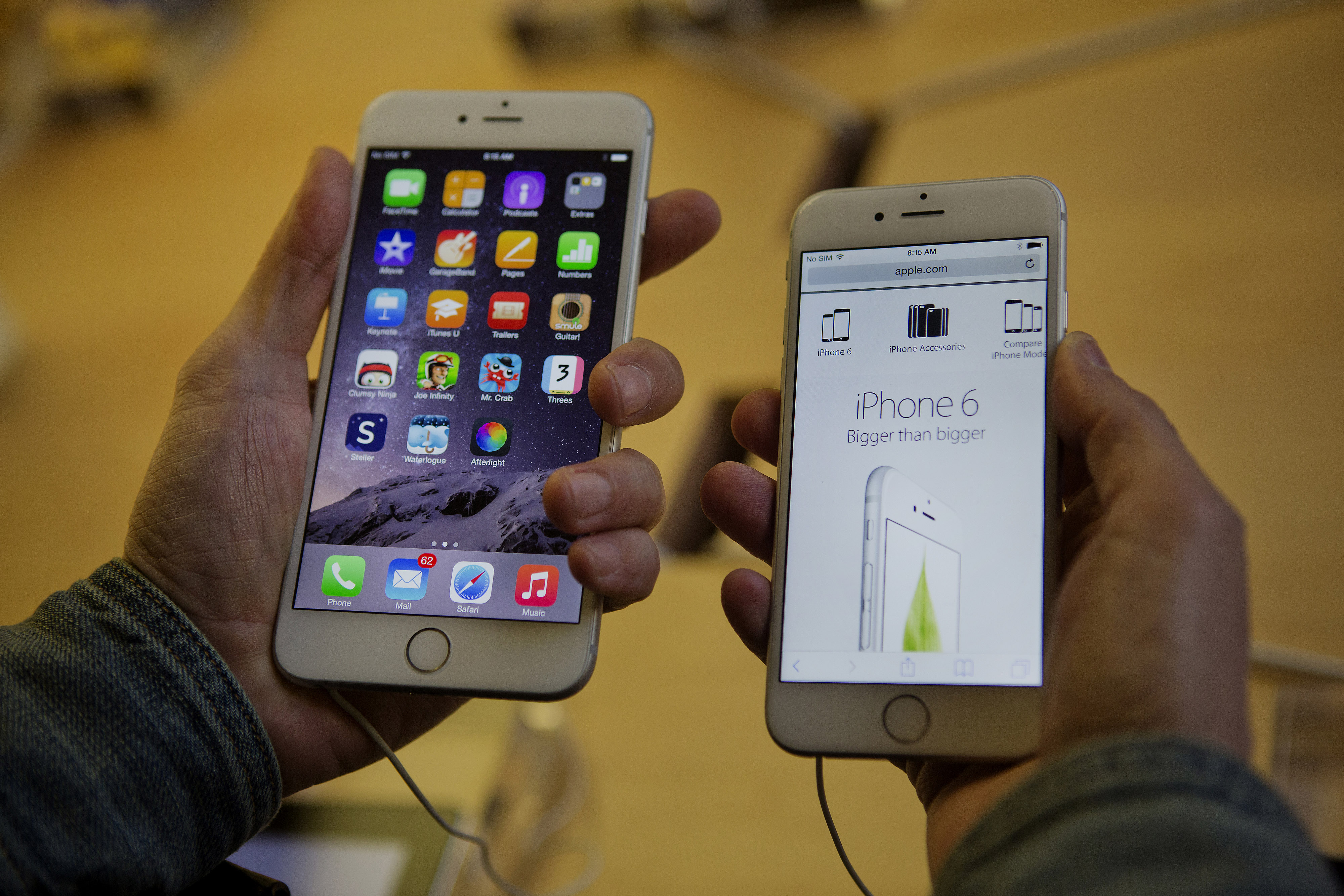 A customer tries to decide between an iPhone 6 Plus, left, and iPhone 6 during the sales launch at the Apple Inc. store in New York on Sept. 19, 2014.