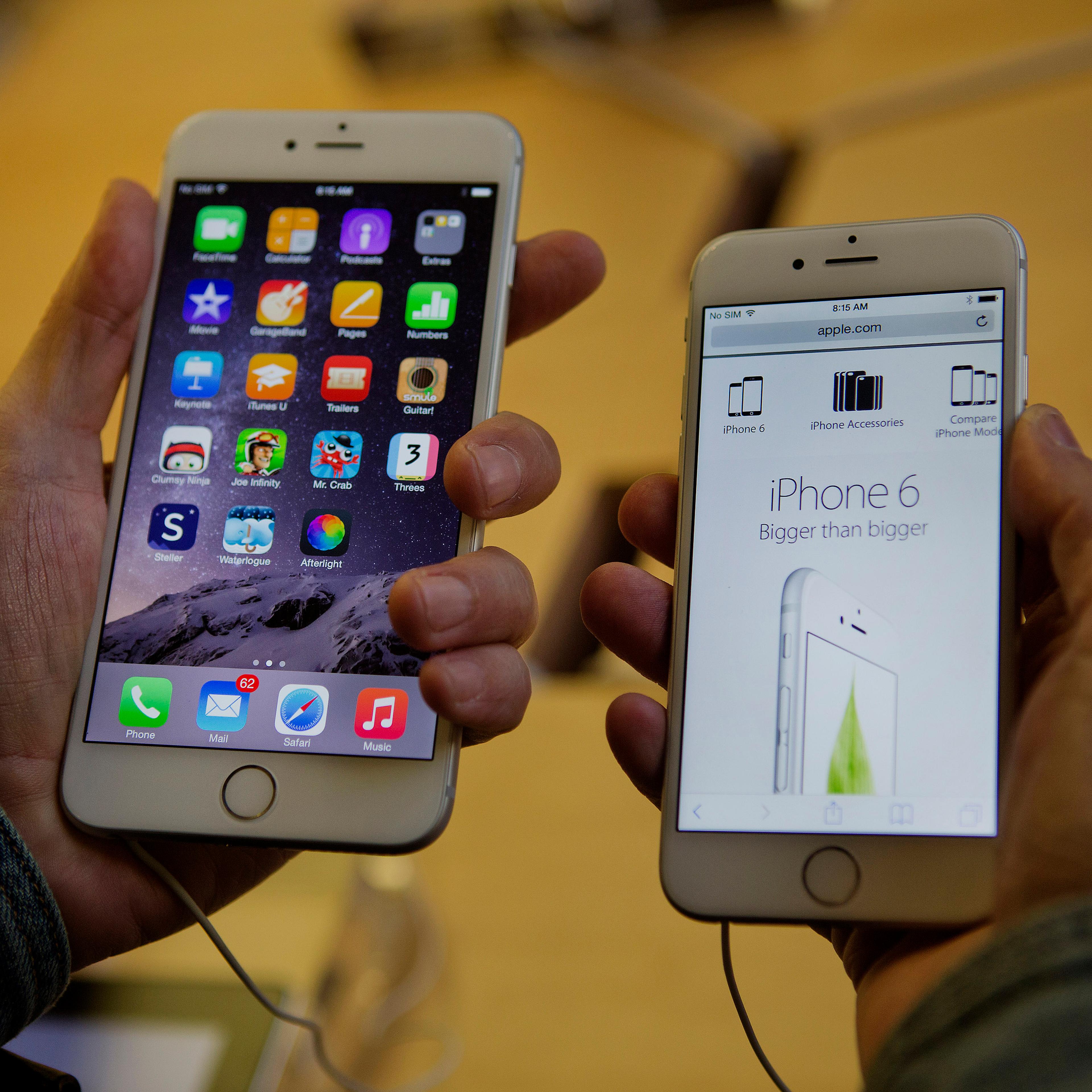A customer tries to decide between an iPhone 6 Plus, left, and iPhone 6 during the sales launch at the Apple Inc. store in New York on Sept. 19, 2014.