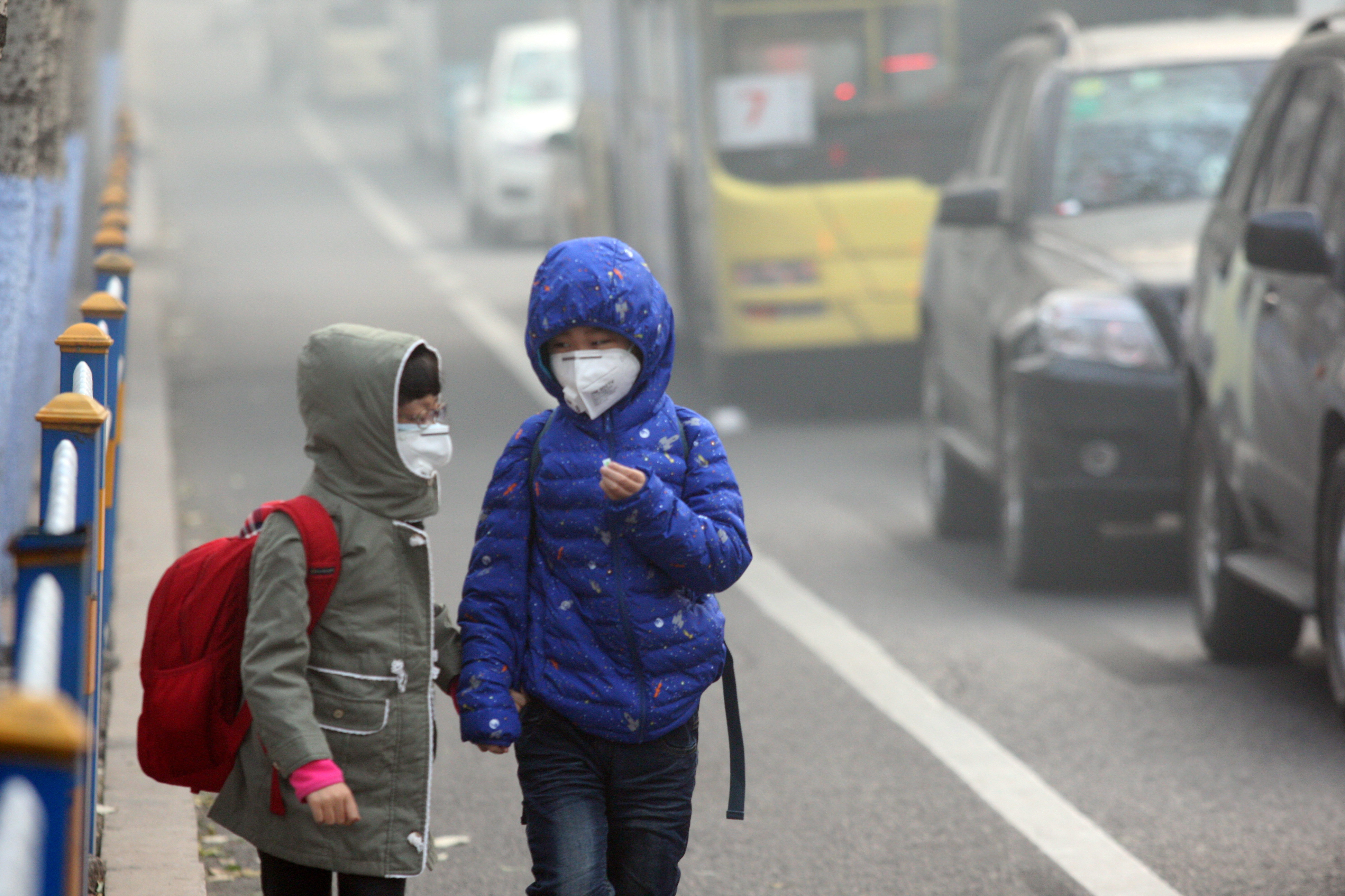 HARBIN, CHINA - NOVEMBER 03: (CHINA OUT) Two children wearing face masks walk in heavy smog on November 3, 2015 in Harbin, Heilongjiang Province of China. Heavy smog stroke northeast China with the visibility in parts of cities reaching less than 50 mete