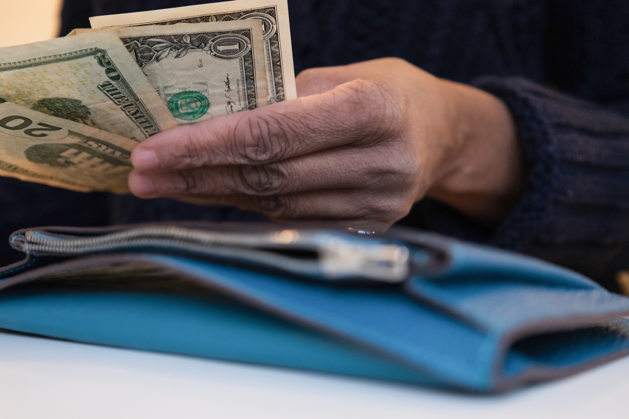 black woman counting money with wallet open on desk