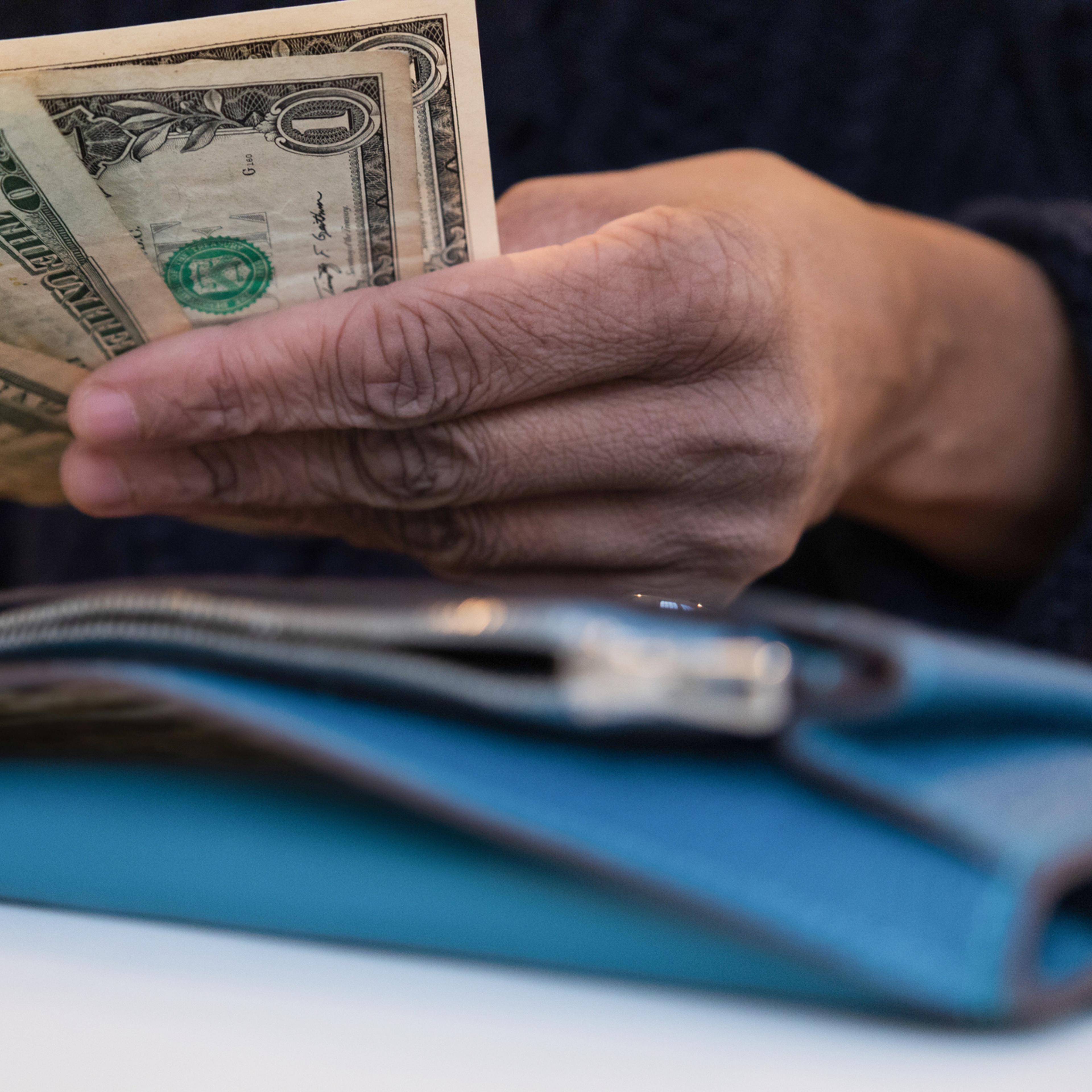 black woman counting money with wallet open on desk