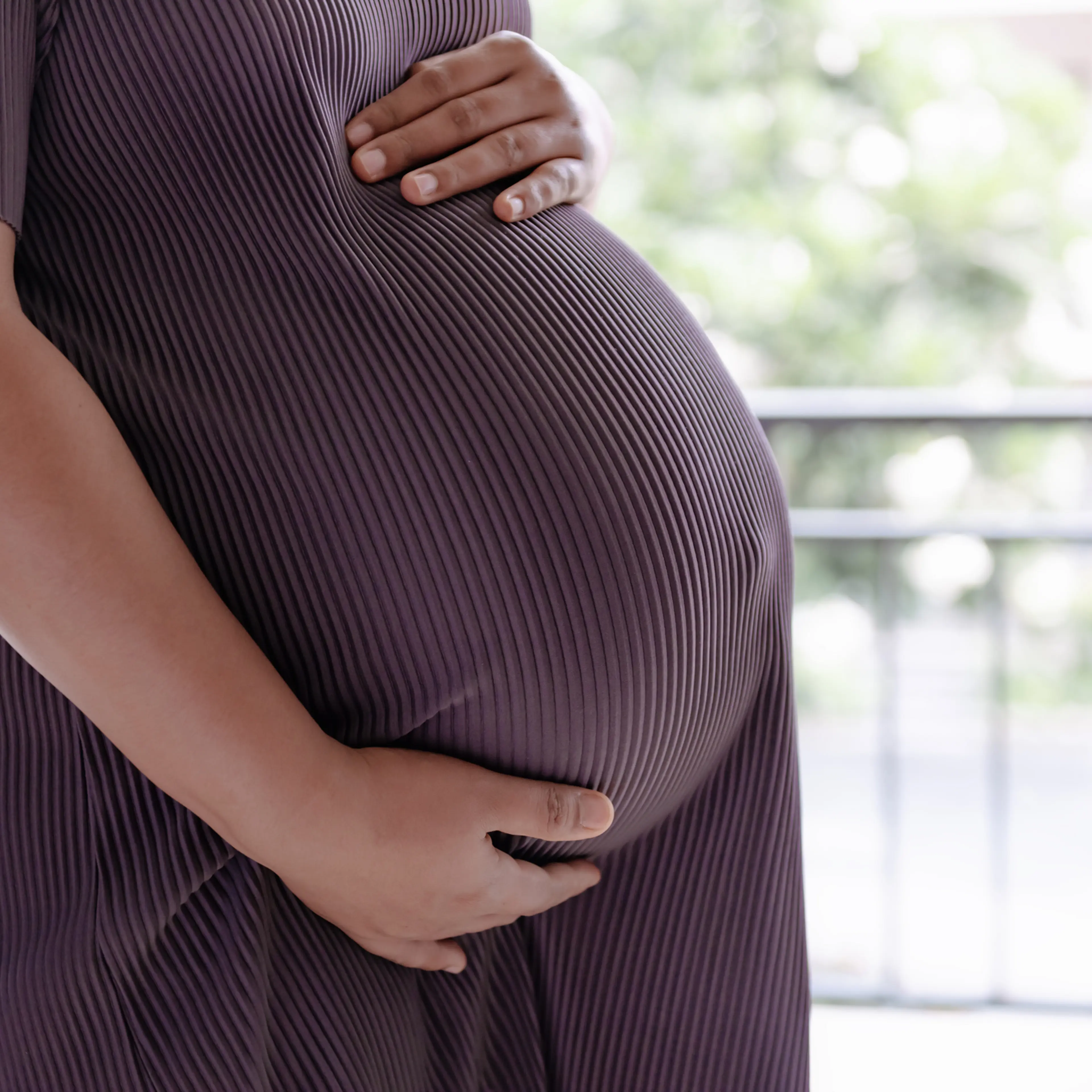 Close-Up midsection of pregnant woman holding her belly. Pregnancy and wellbeing concepts