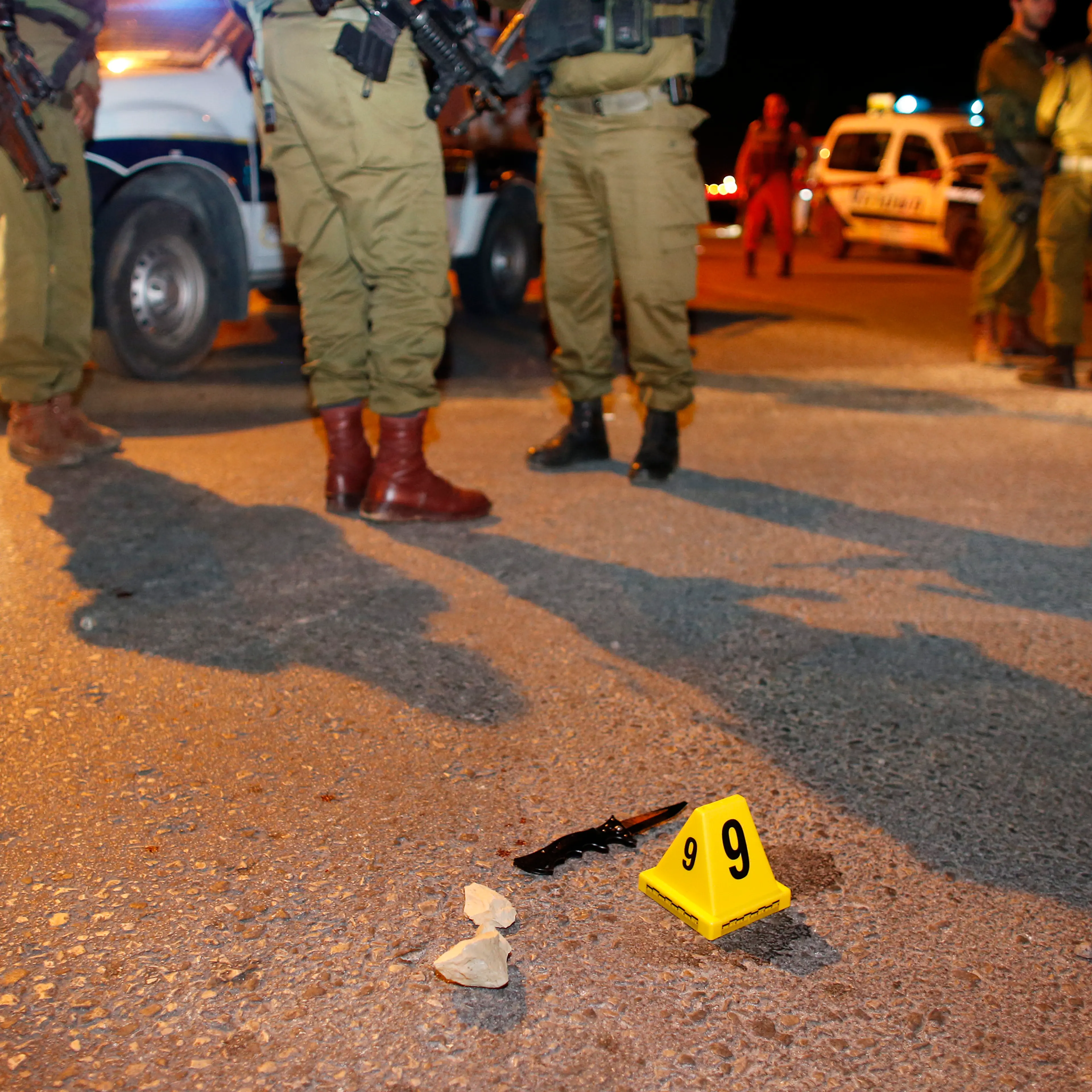 Israeli soldiers stand near a knife at the scene of a stabbing attack near the West Bank Jewish settlement of Alon Shvut