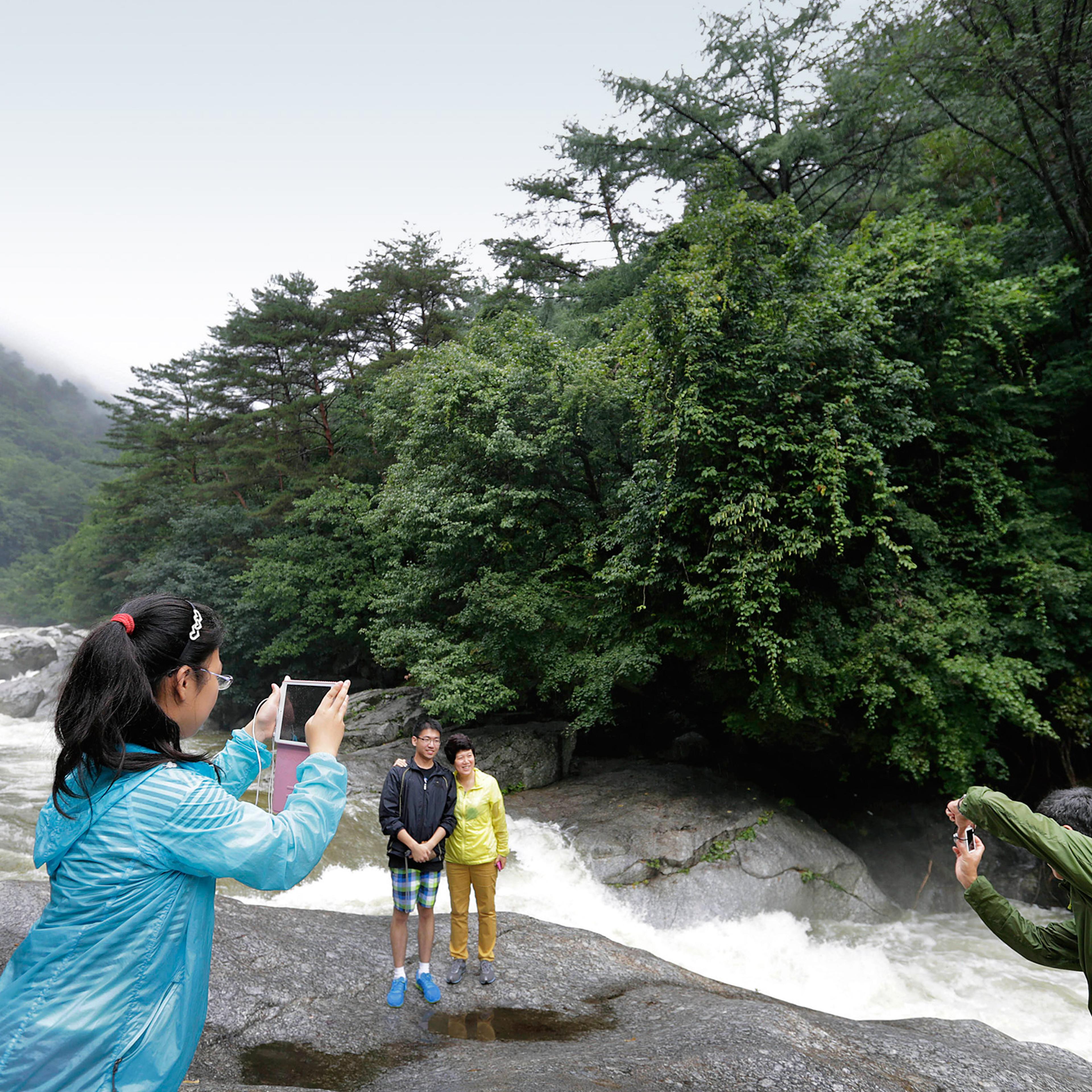 Chinese visitors take photographs at rapids at Mount Myonhyang, a North Korean tourist attraction