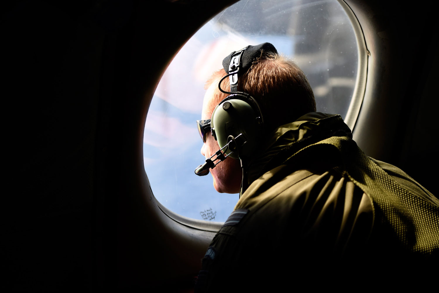 A crew member looks out an observation window aboard a Royal New Zealand Air Force P3 Orion maritime search aircraft as it flies over the southern Indian Ocean looking for debris from missing Malaysian Airlines flight MH 370 April 11, 2014.