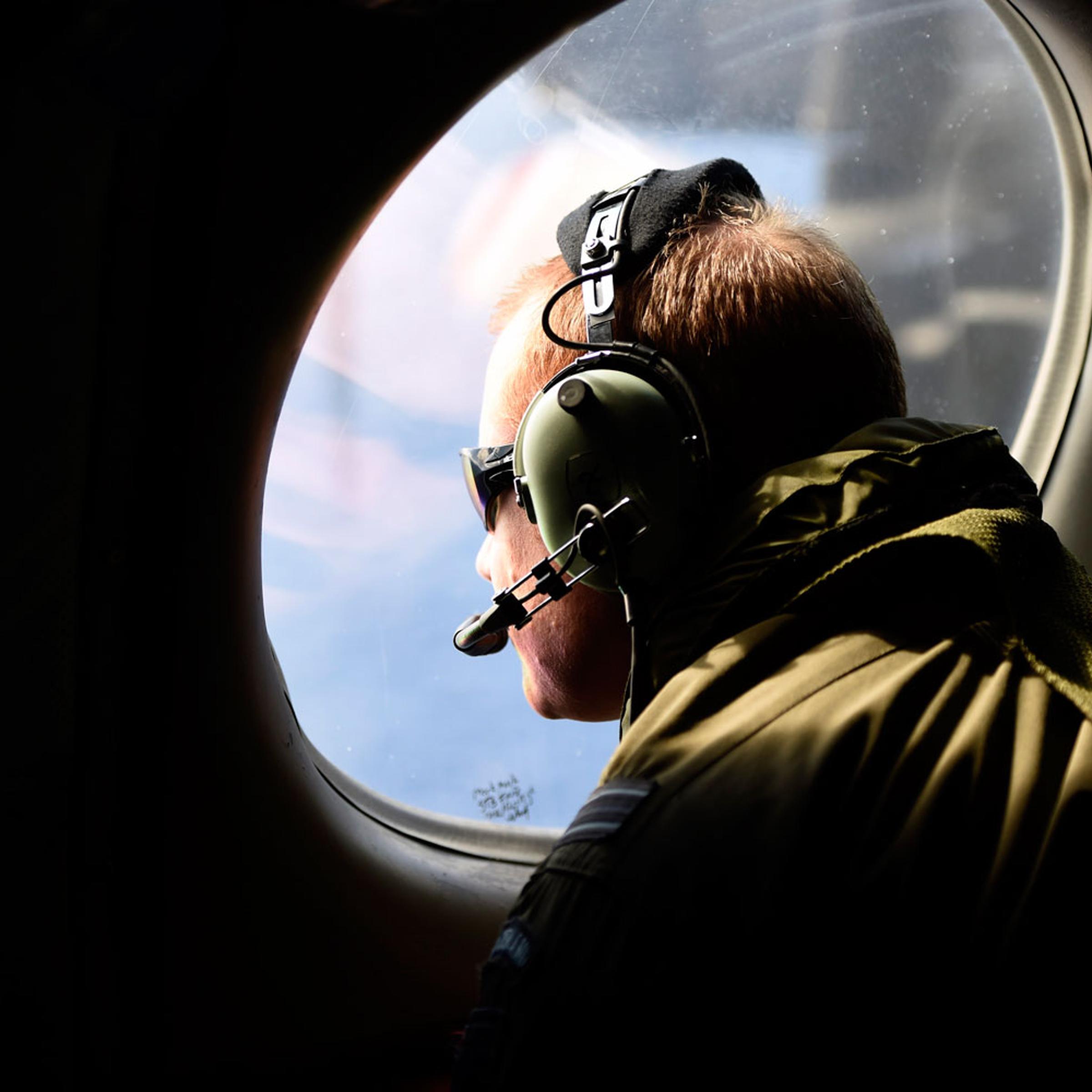 A crew member looks out an observation window aboard a Royal New Zealand Air Force P3 Orion maritime search aircraft as it flies over the southern Indian Ocean looking for debris from missing Malaysian Airlines flight MH 370 April 11, 2014.