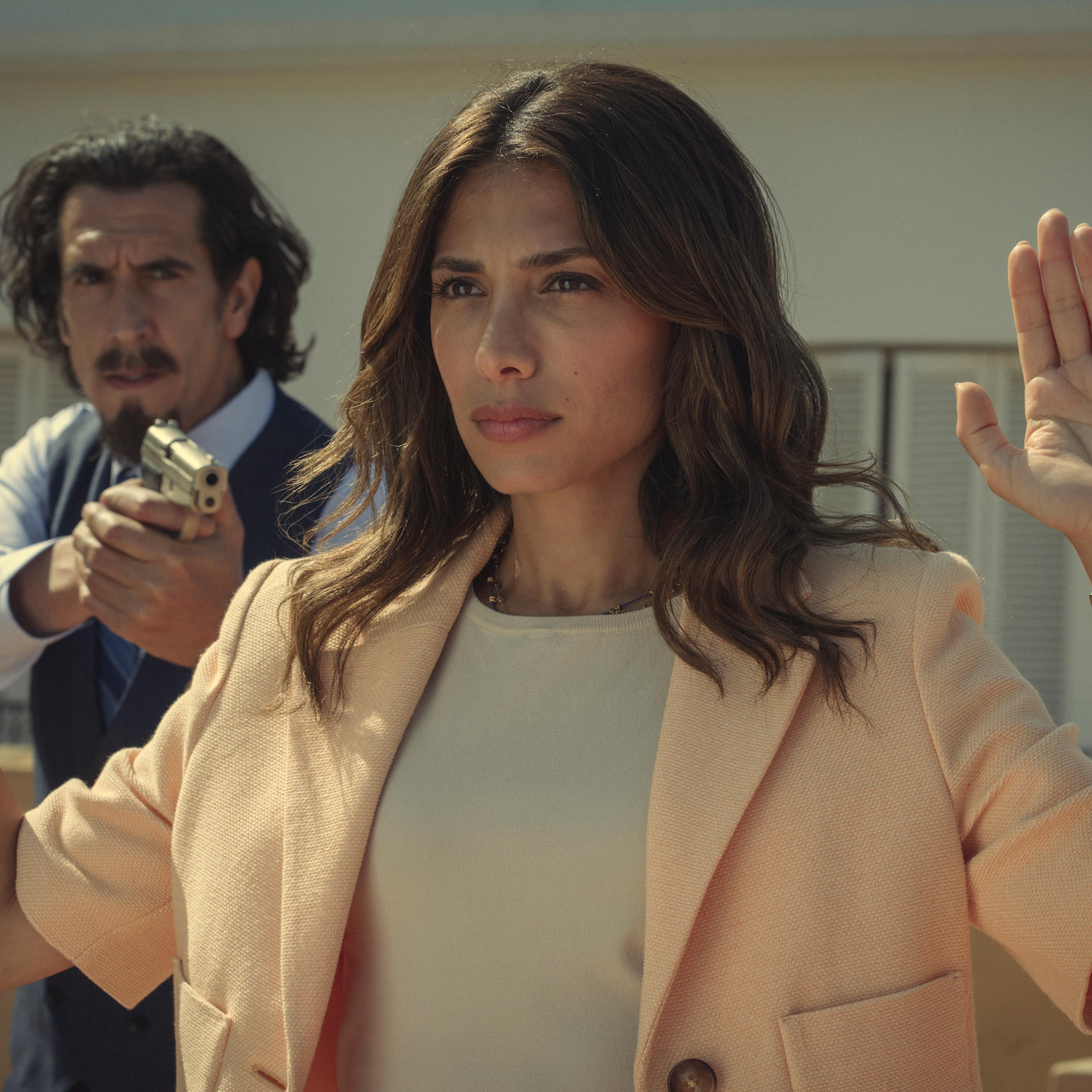 Augustín (Rodrigo Poisón) holds Erin (Evin Ahmad) at gunpoint.