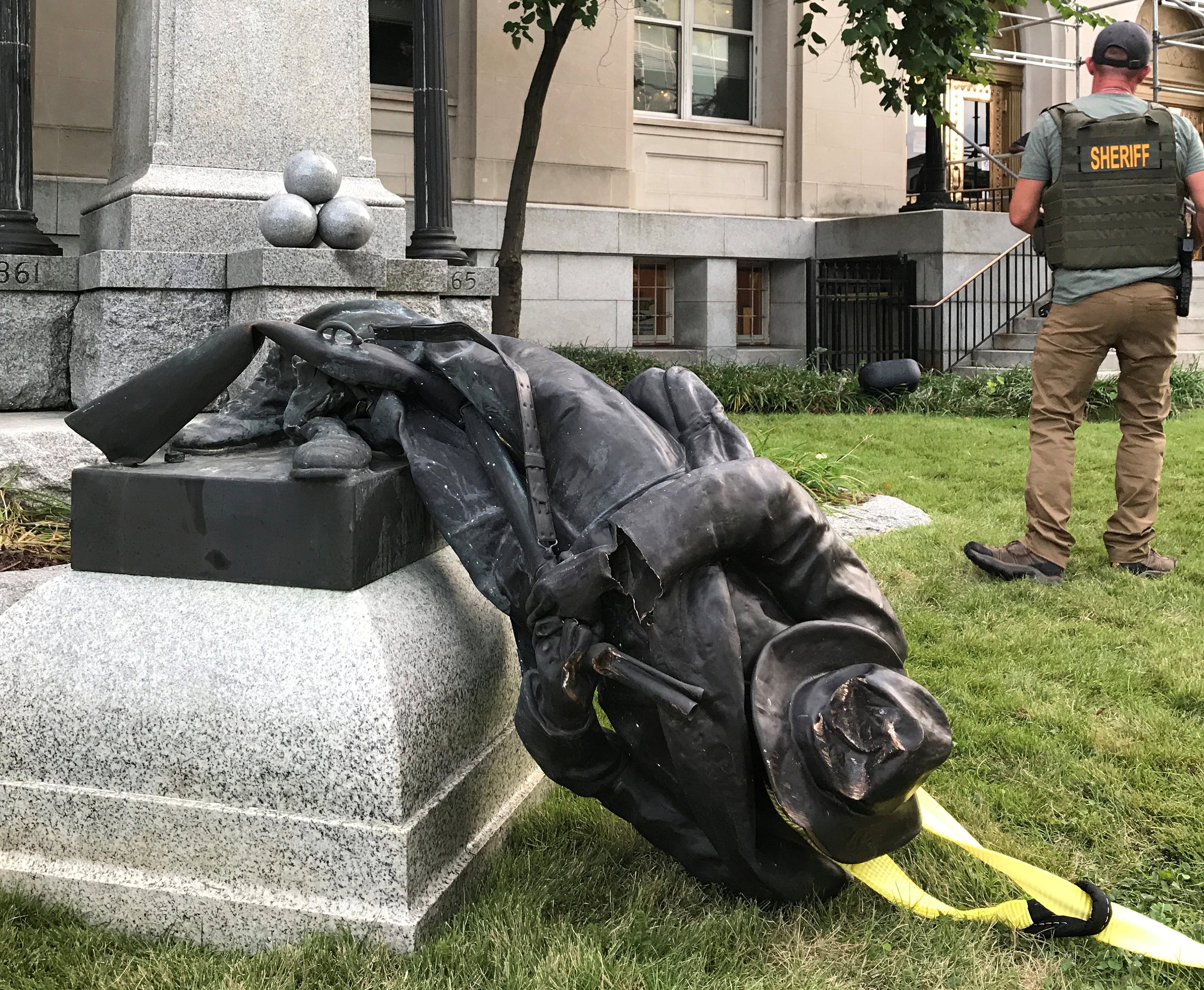 A Sheriff's deputy stands near the toppled statue of a Confederate soldier in front of the old Durham County Courthouse in Durham