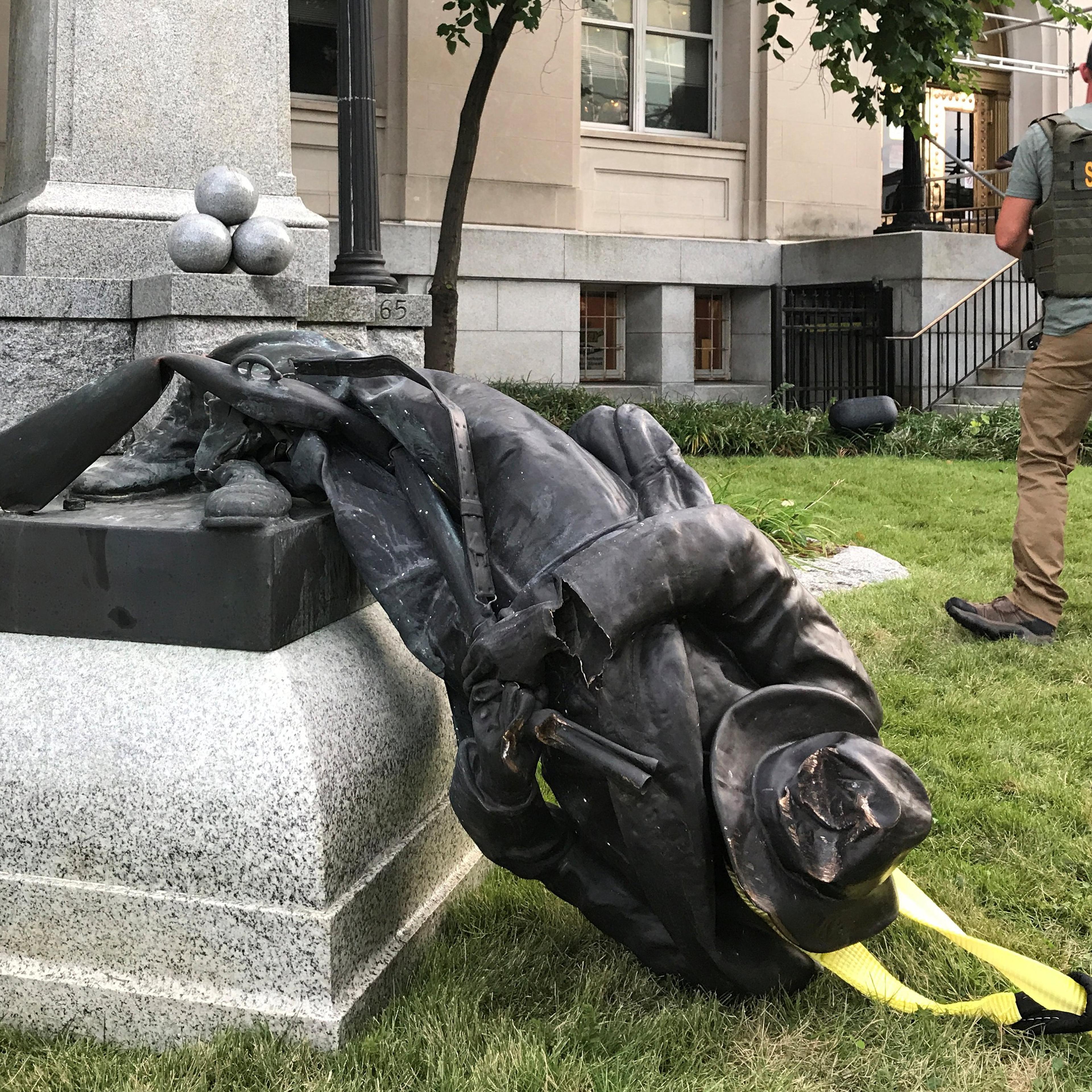 A Sheriff's deputy stands near the toppled statue of a Confederate soldier in front of the old Durham County Courthouse in Durham