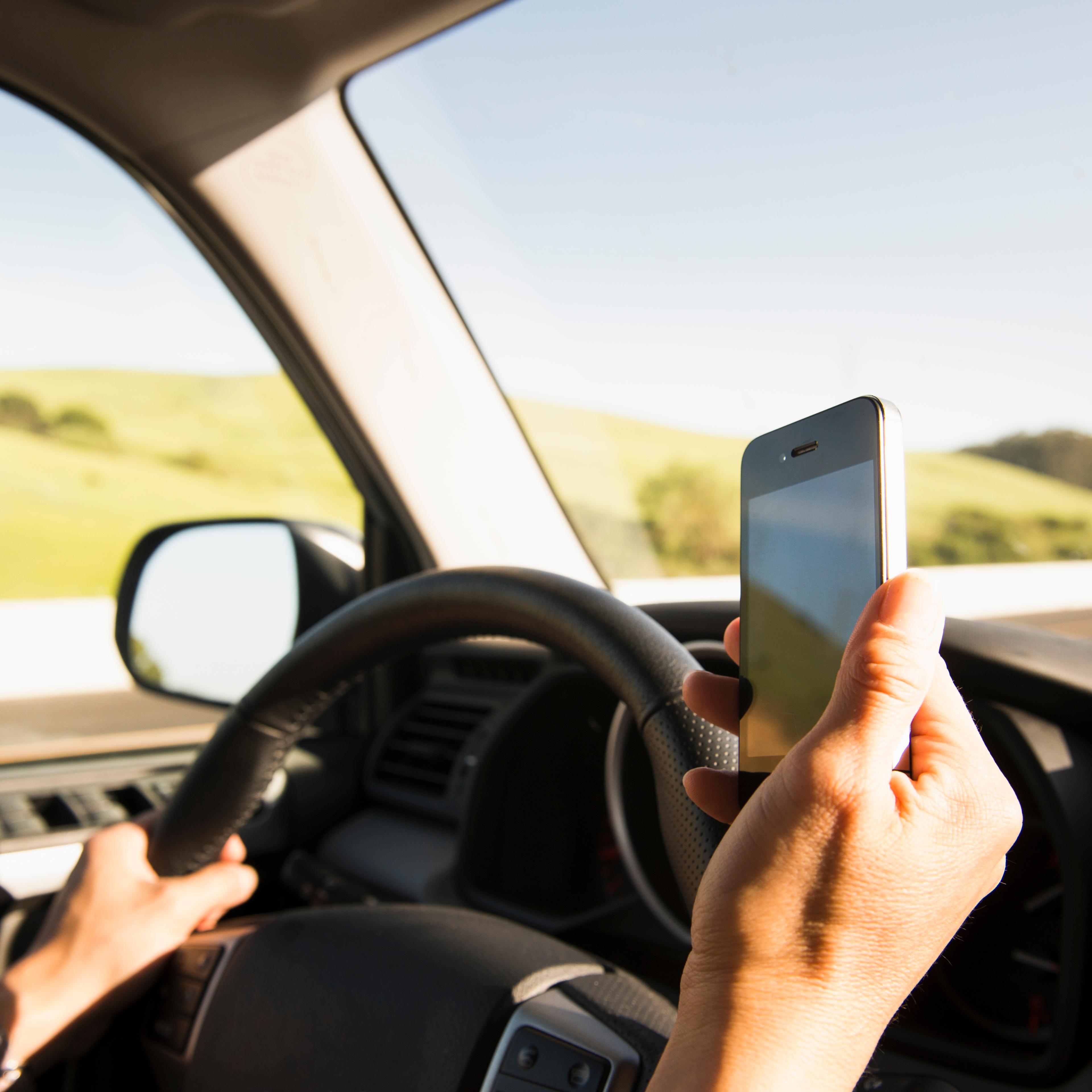 Hispanic woman driving and using cell phone