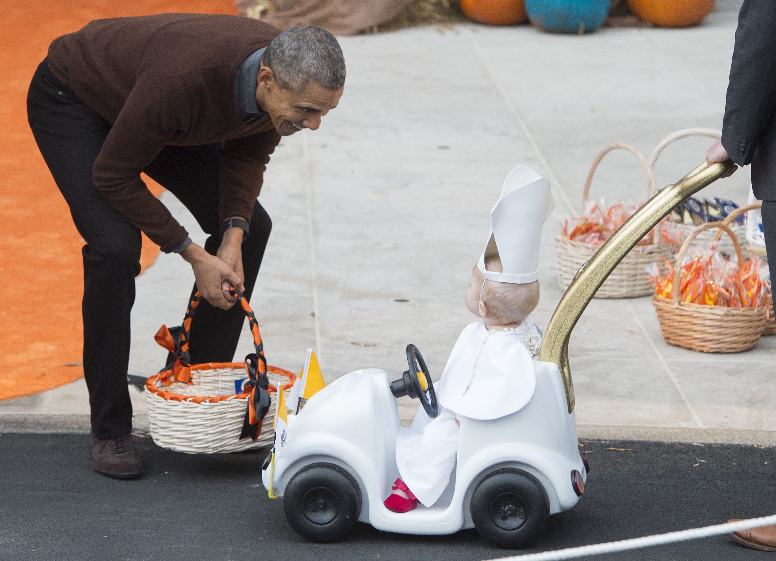 US President Barack Obama greets a young child dressed as the Pope and riding in a "Popemobile" as he hands out treats to children trick-or-treating for Halloween on the South Lawn of the White House in Washington, DC, October 30, 2015. AFP PHOTO / SAUL 