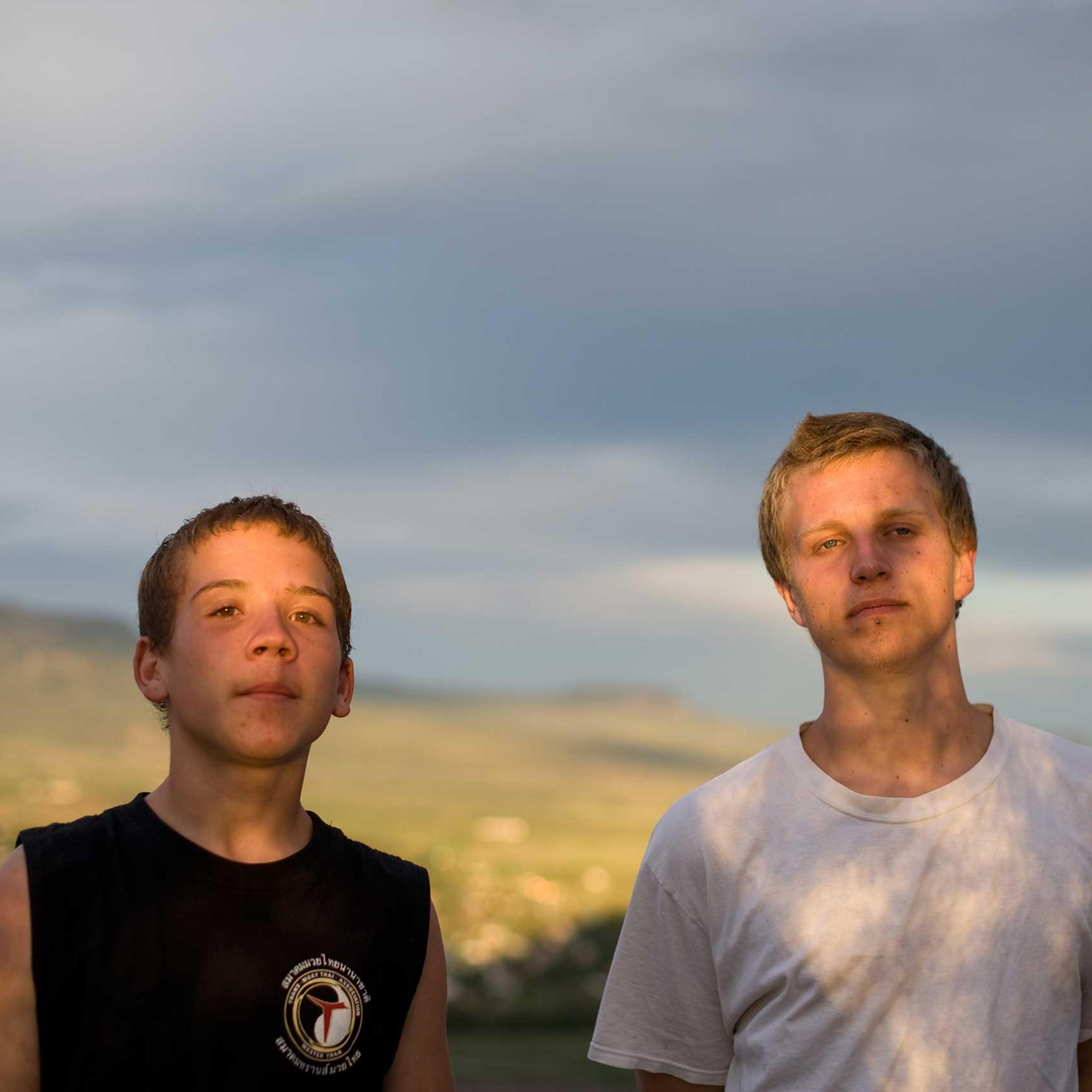 Brothers Vinny and David stand together as the sky darkens before a summer storm.