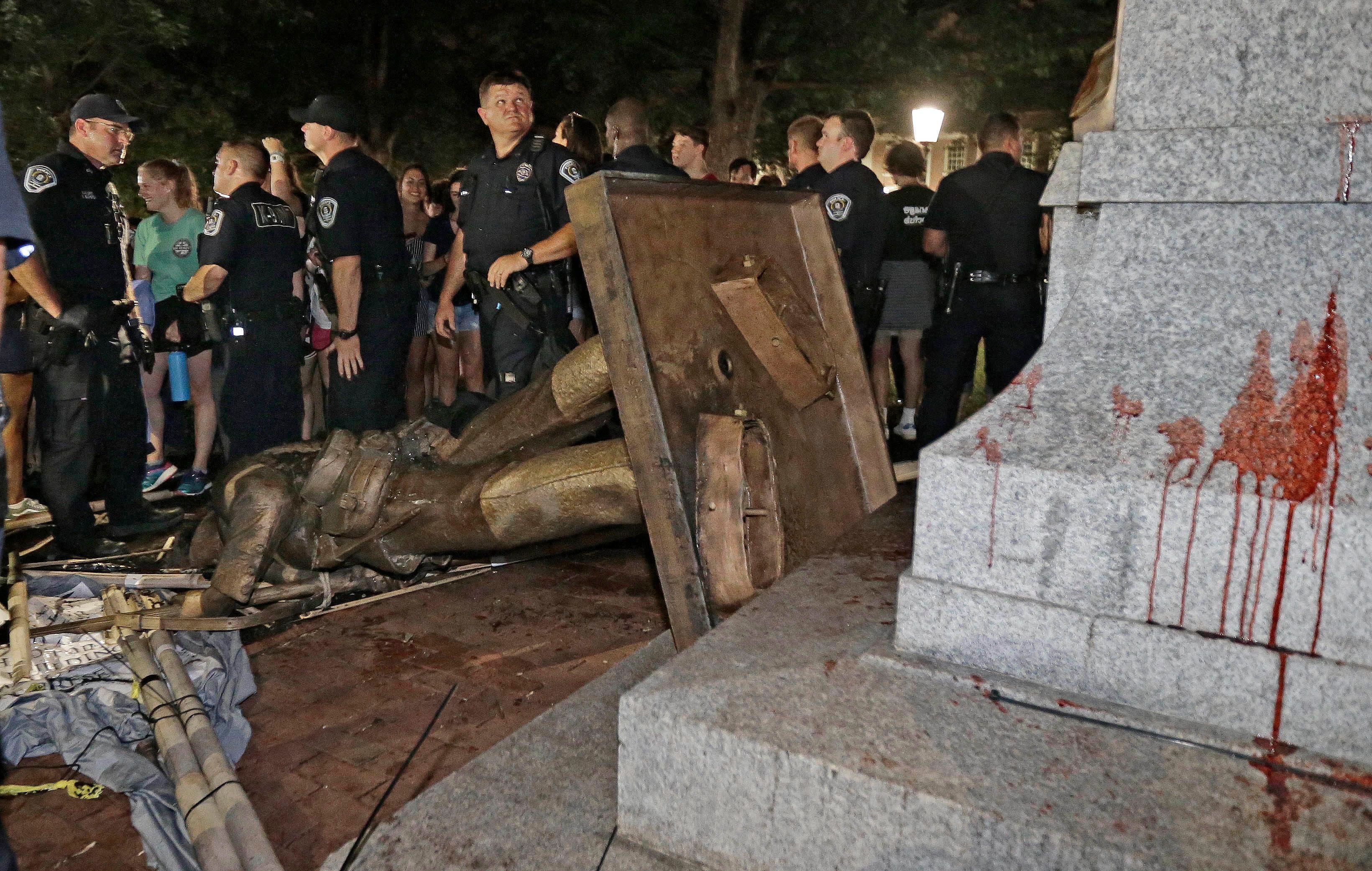 Silent Sam destroyed on the ground, surrounded by police