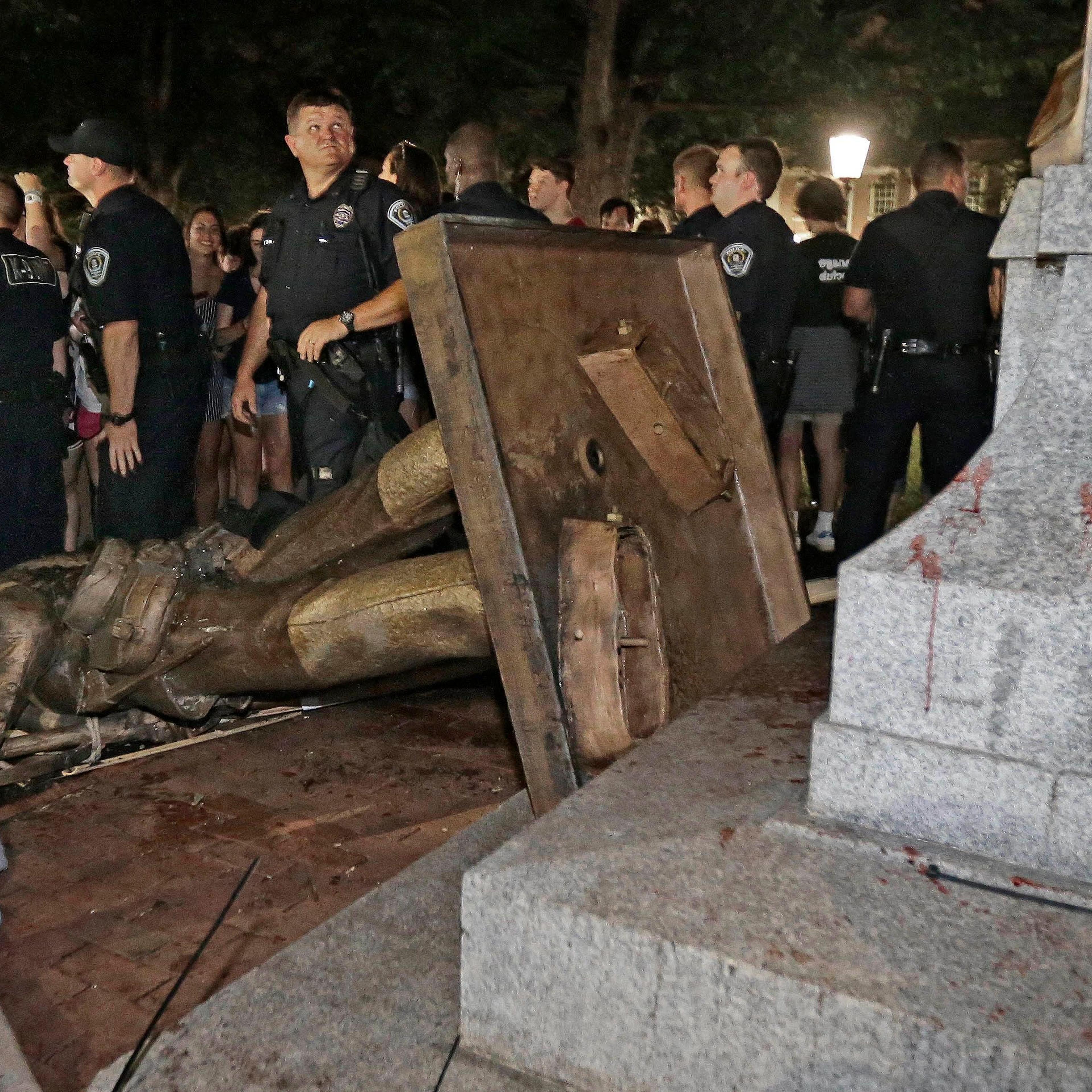 Silent Sam destroyed on the ground, surrounded by police