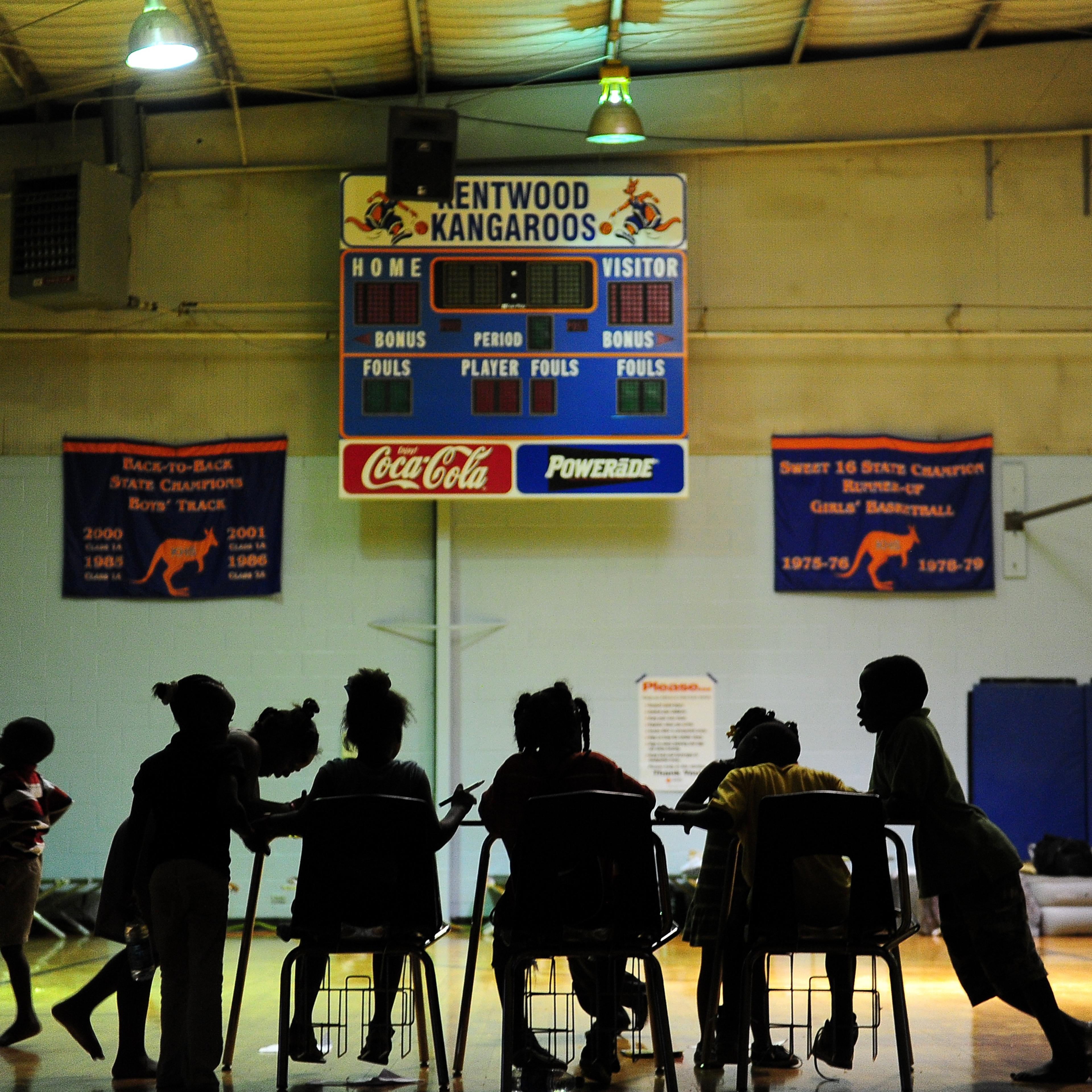Children try to do their homework at an evacuation shelter in a high school gymnasium in Kentwood, Louisiana on August 30, 2012.