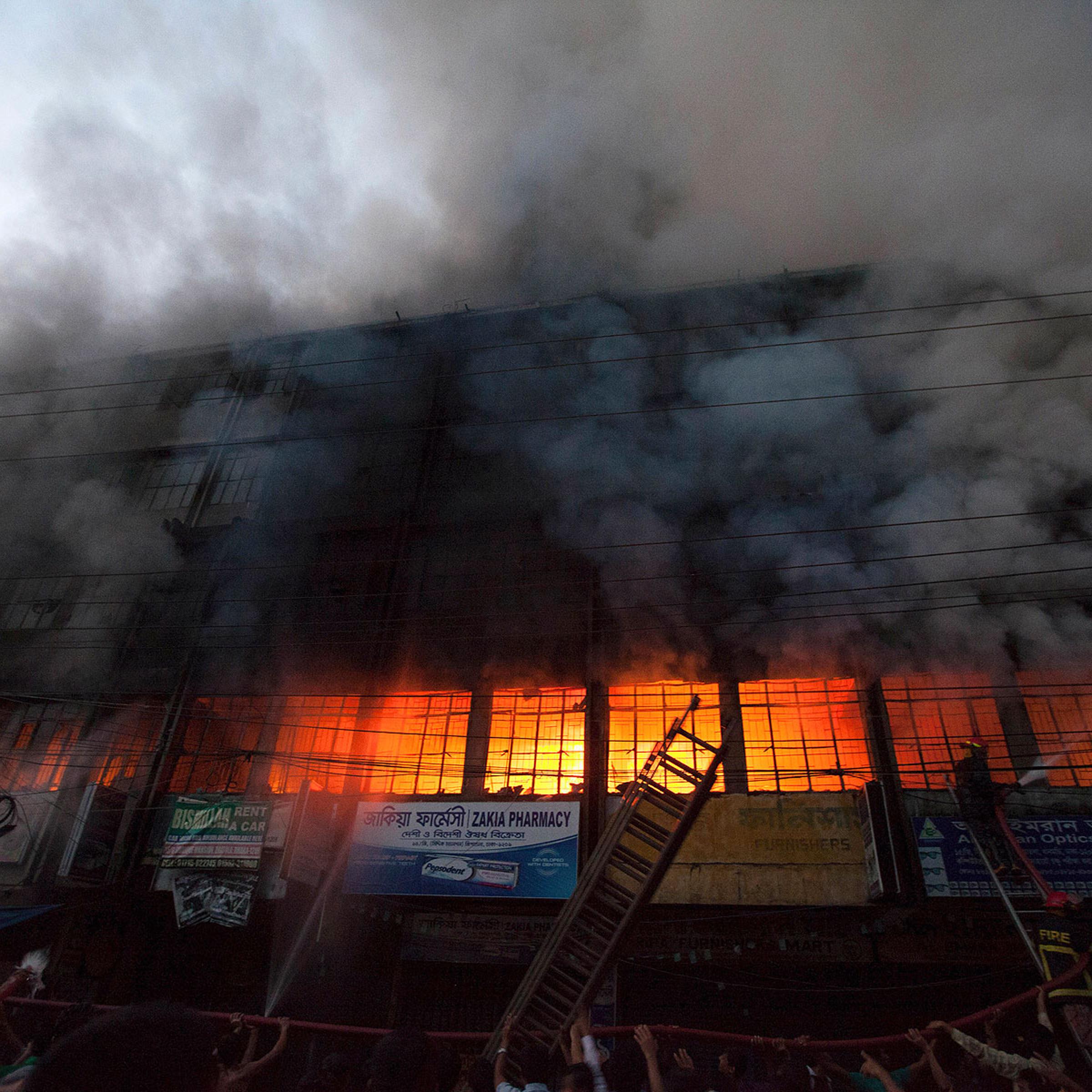 Locals and fire-fighters try to control a fire at a garment factory in Dhaka March 6, 2014