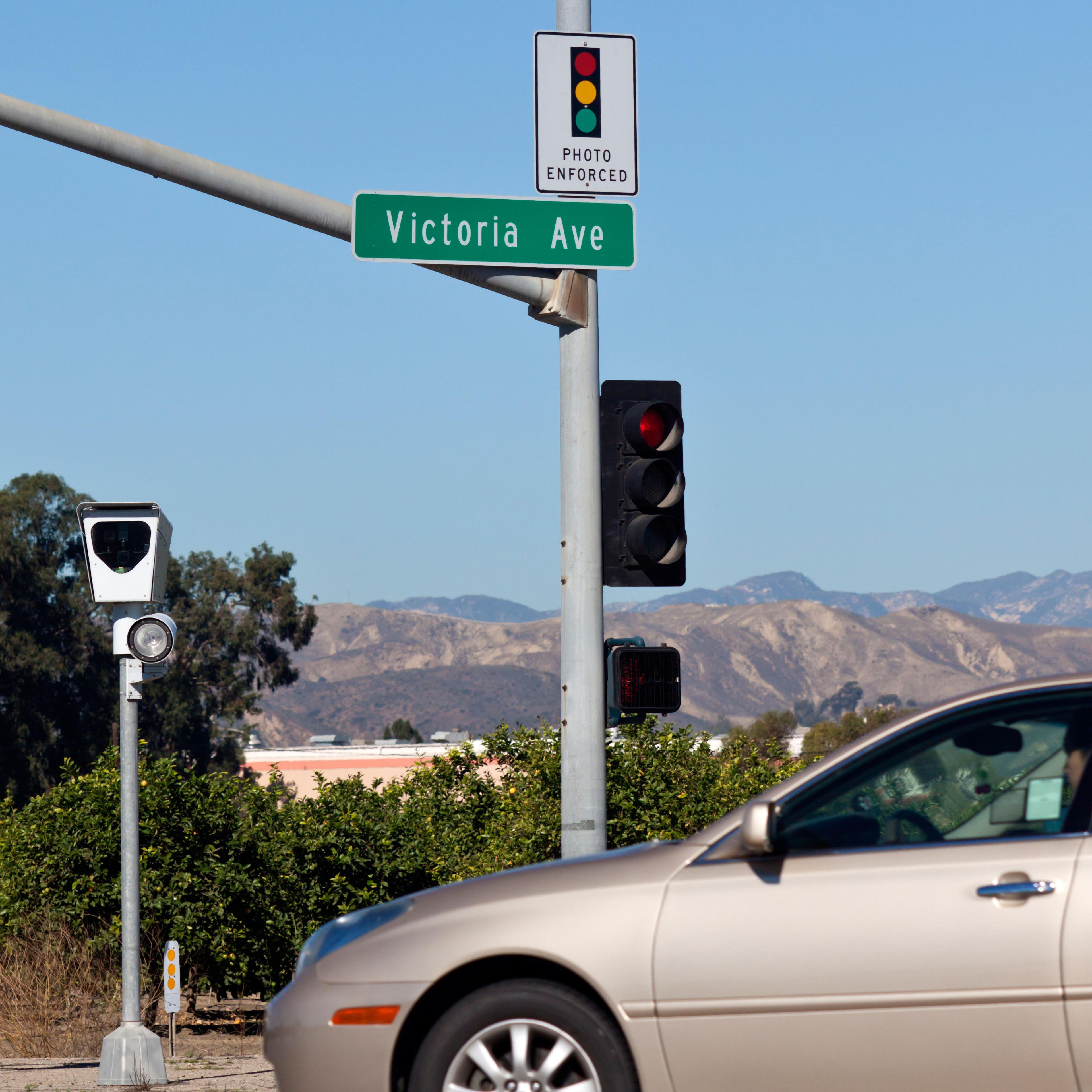 Car driving through intersection with photo enforced camera radar.