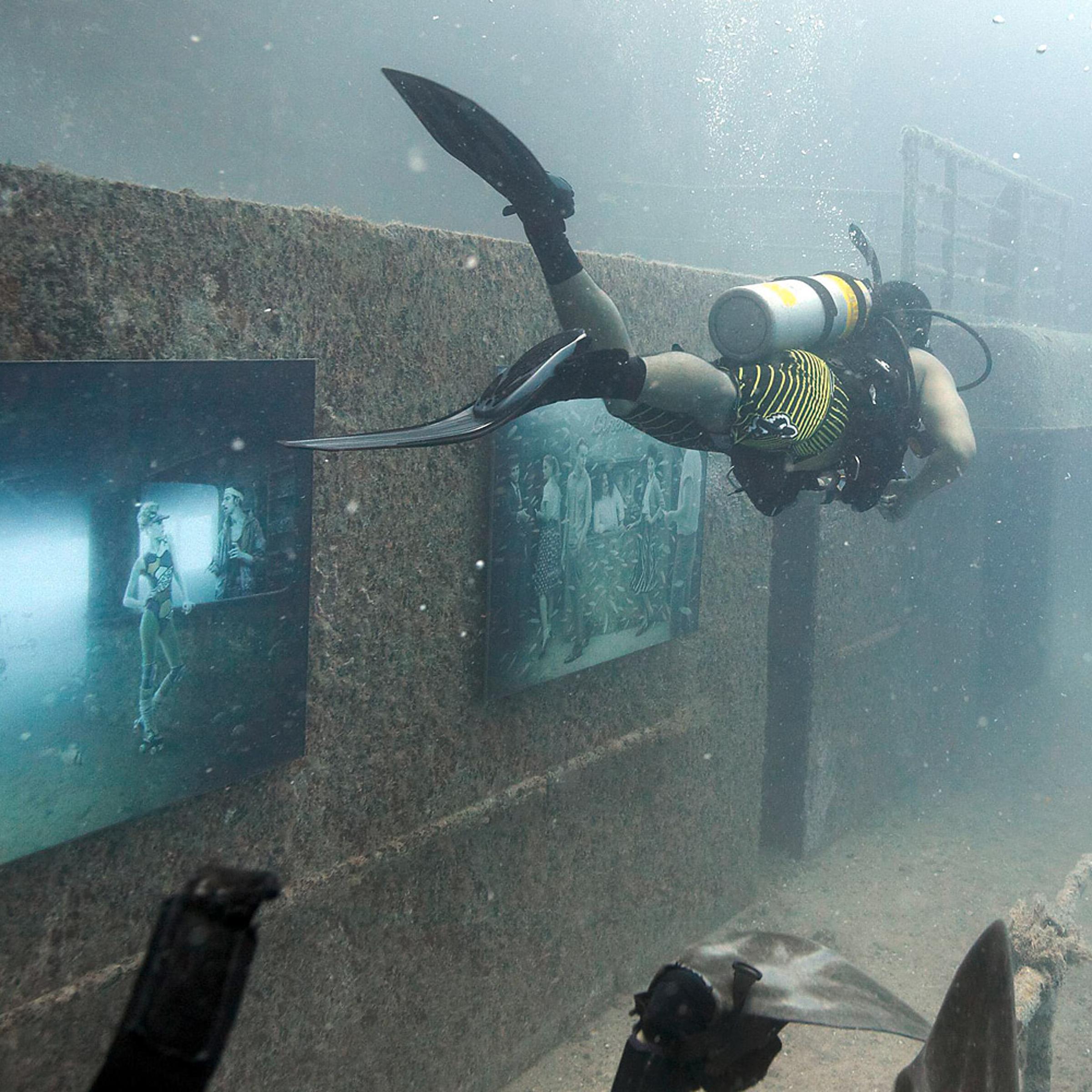 Divers pass photographs by Andreas Franke along the deck of Gen. Hoyt S. Vandenberg artificial reef, August 4, 2011.