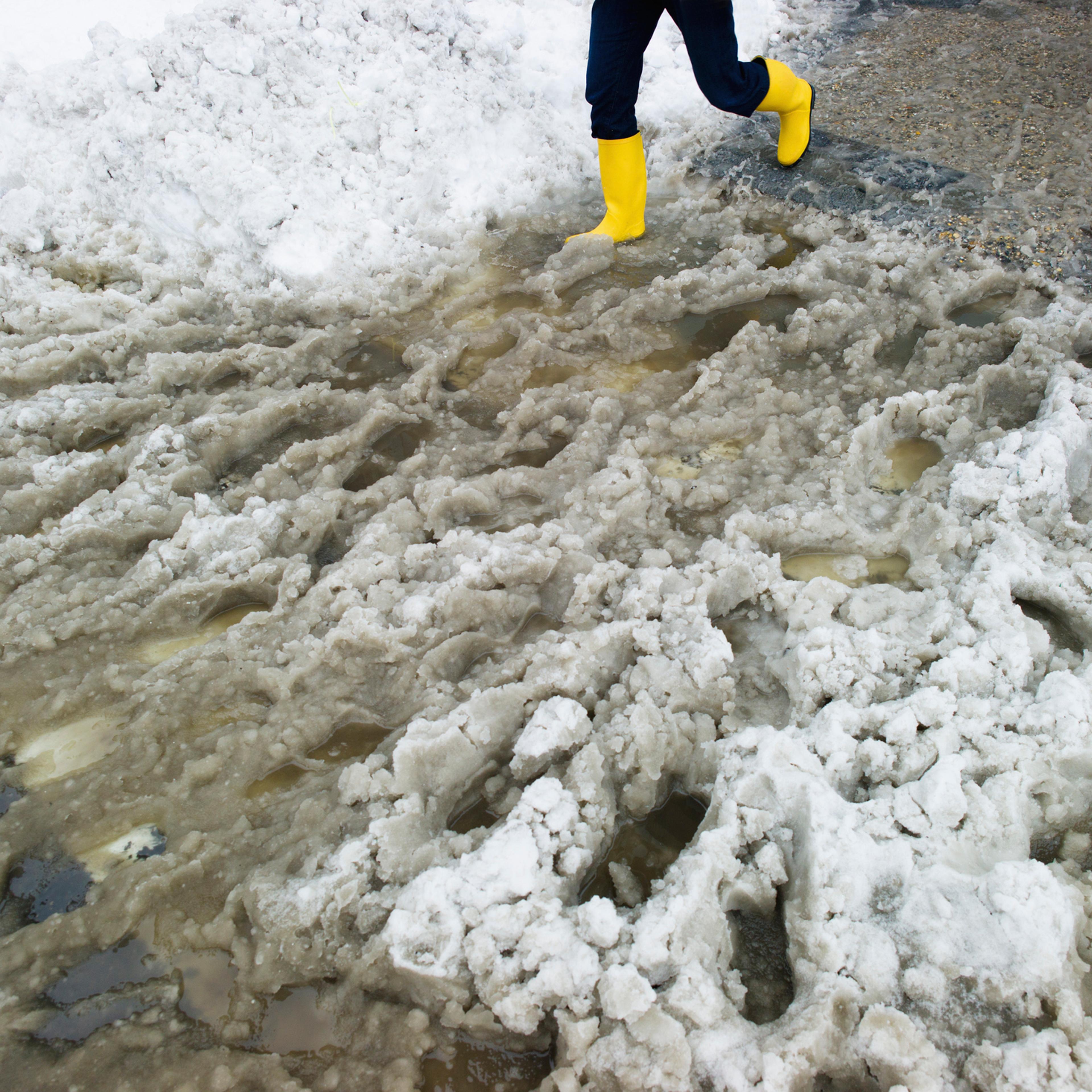 USA, New York, New York City, legs of person in yellow rubber boots walking in slush