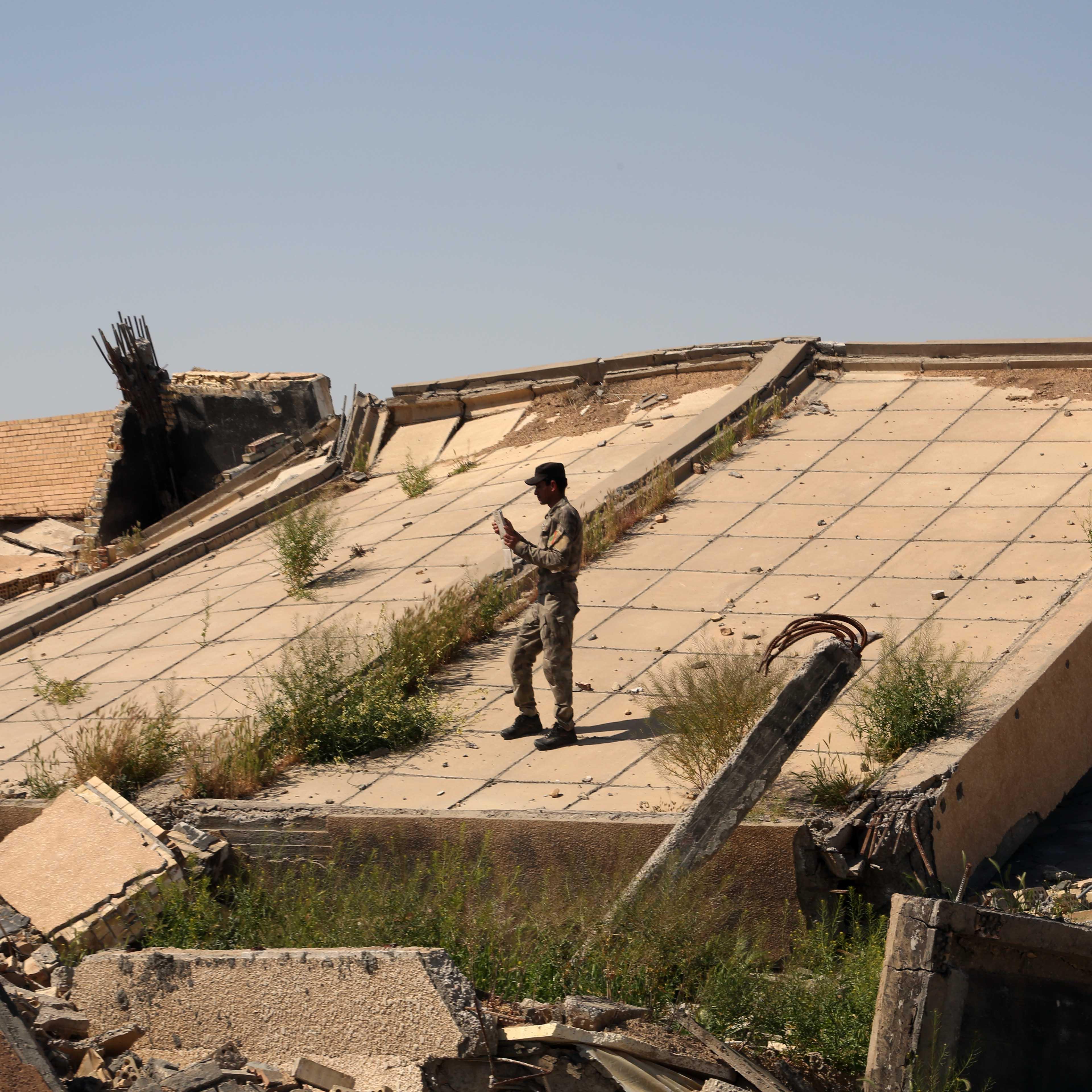 An Iraqi soldier takes photos of the demolished tomb of former Iraqi president, Saddam Hussein, in Tikrit, Iraq, March 15, 2015