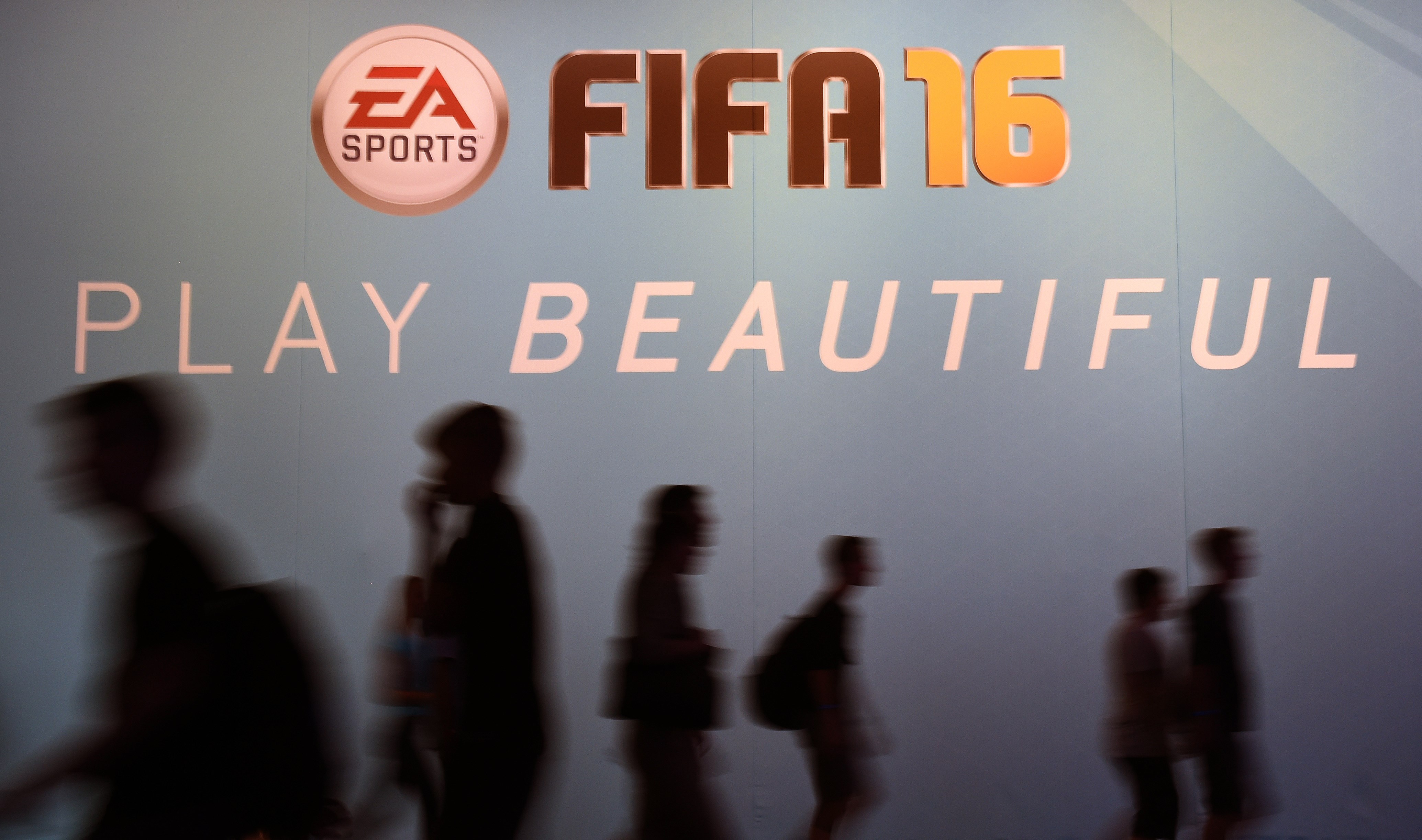 Visitors walk past an ad for the FIFA 16 football game at the Gamescom fair in Cologne, western Germany on August 7, 2015.