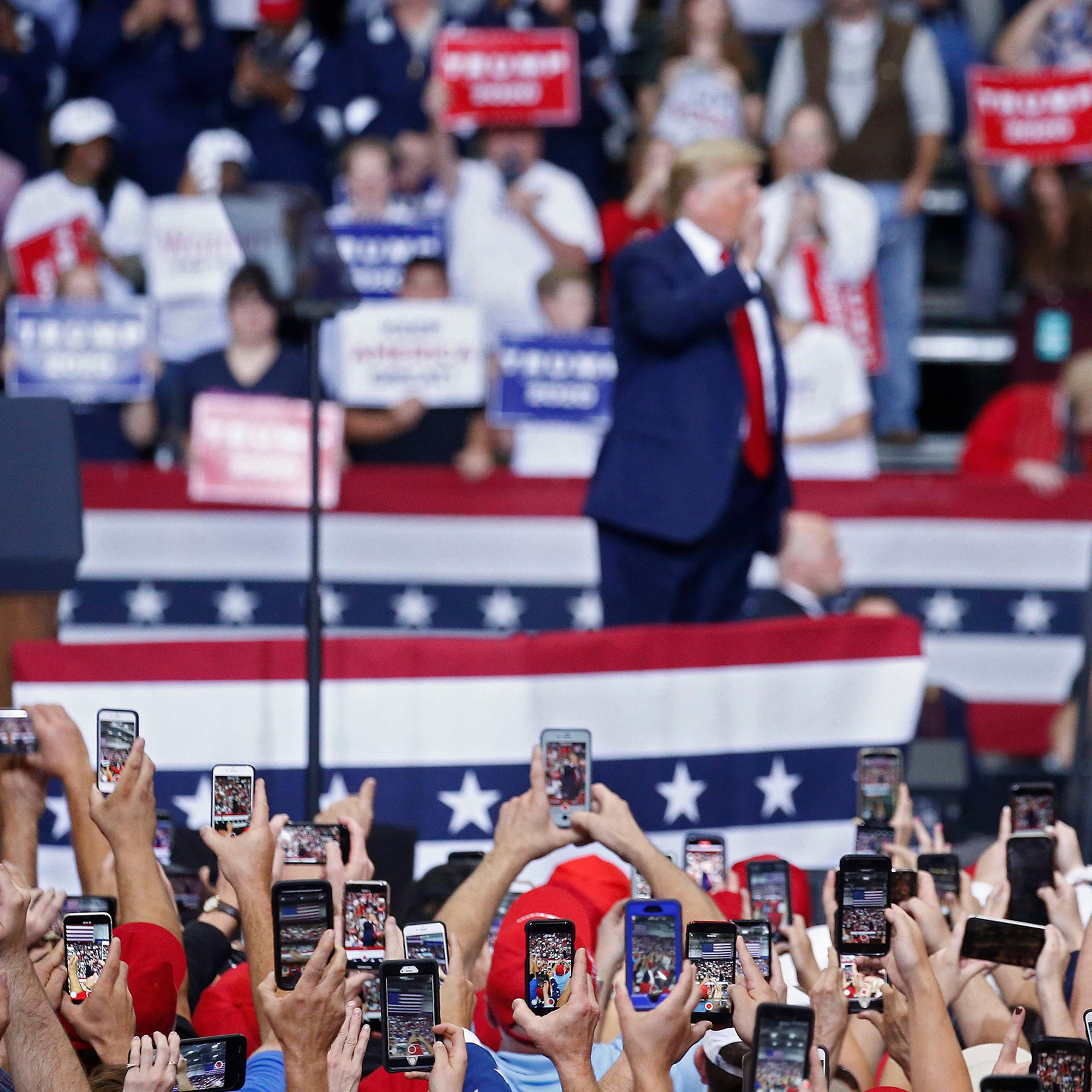 People use their phones to photograph President Donald Trump as he addresses a rally in Monroe, La., on Nov. 6
